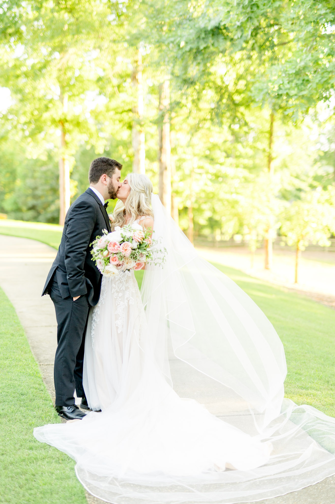 Groom kisses bride as her veil blows in the wind.