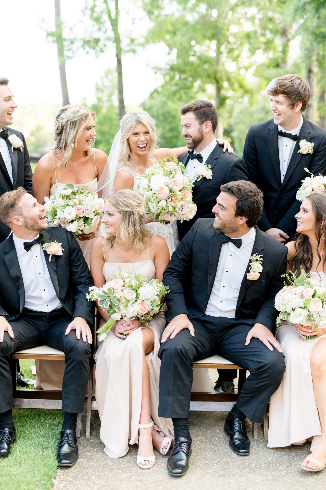 Bride and groom laugh while surrounded by their wedding party.