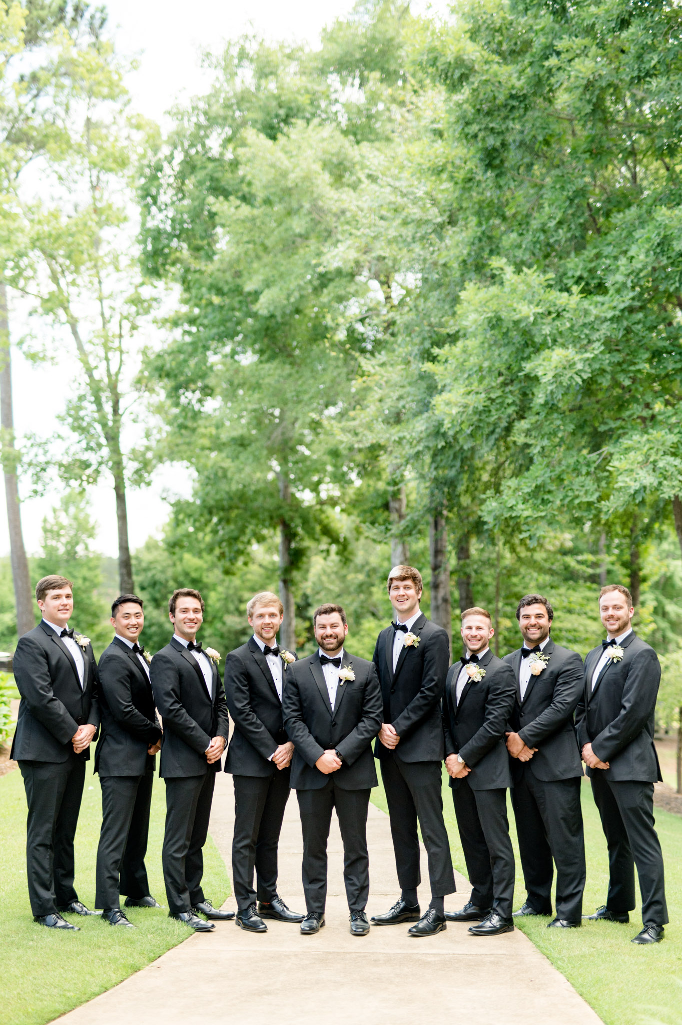Groom stands with groomsmen smile at camera.