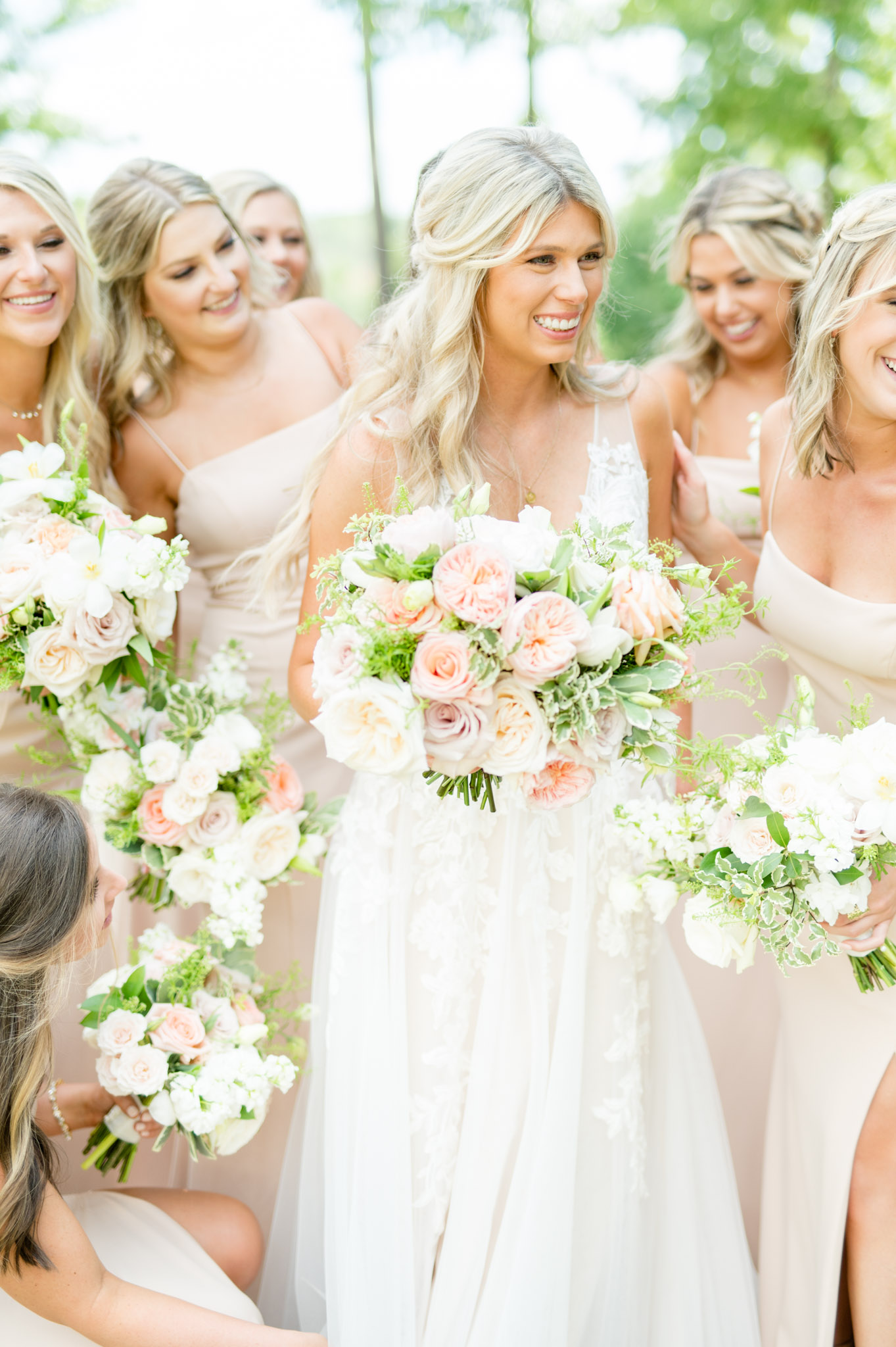 Bride is surrounded by smiling bridesmaids.