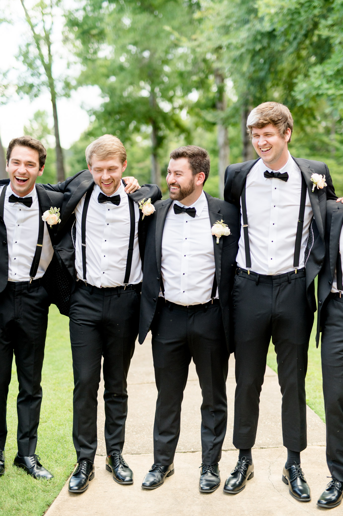 Groom puts arms over groomsmen and smiles.