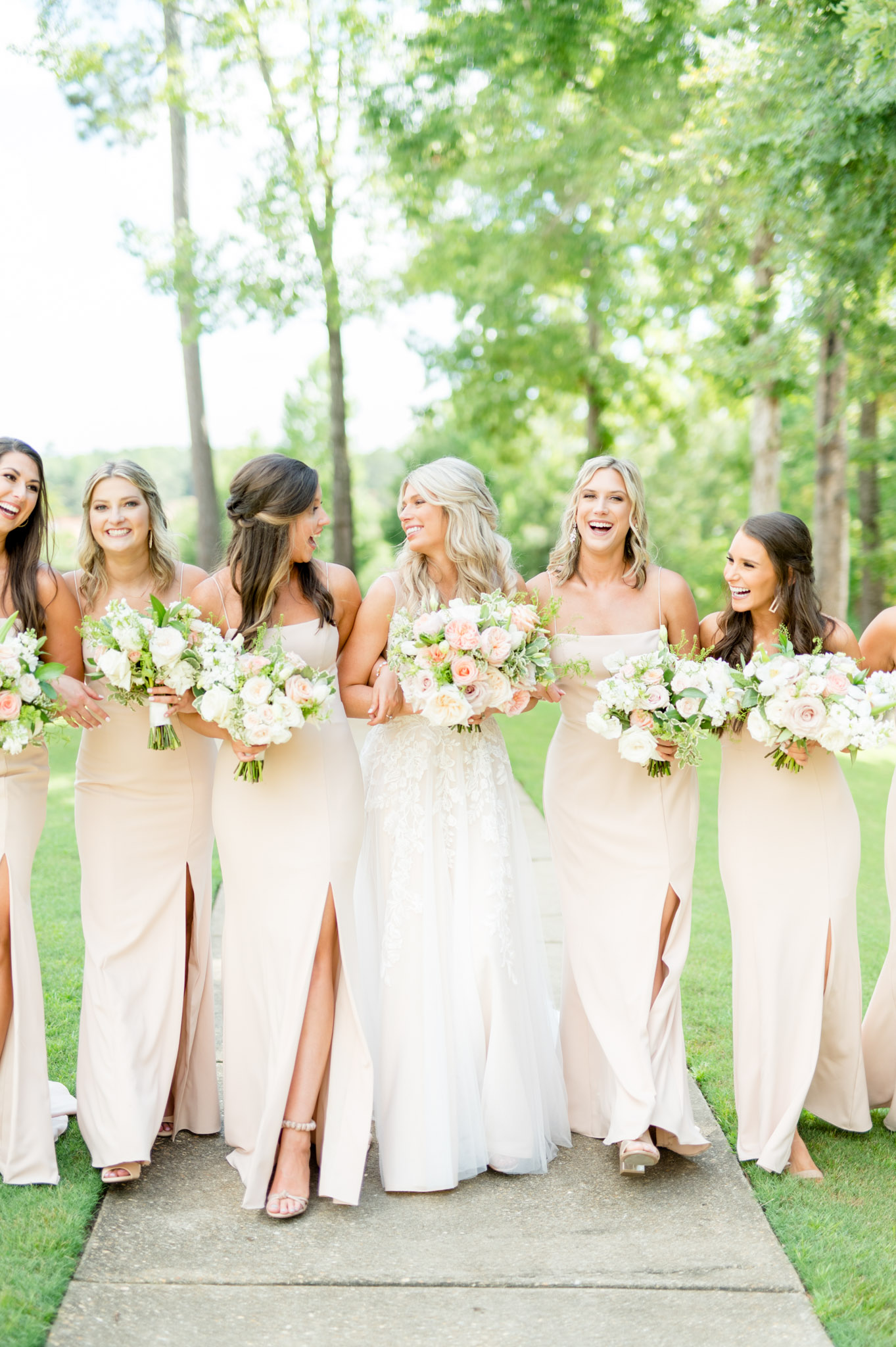 Bride laughs with bridesmaids as they walk.