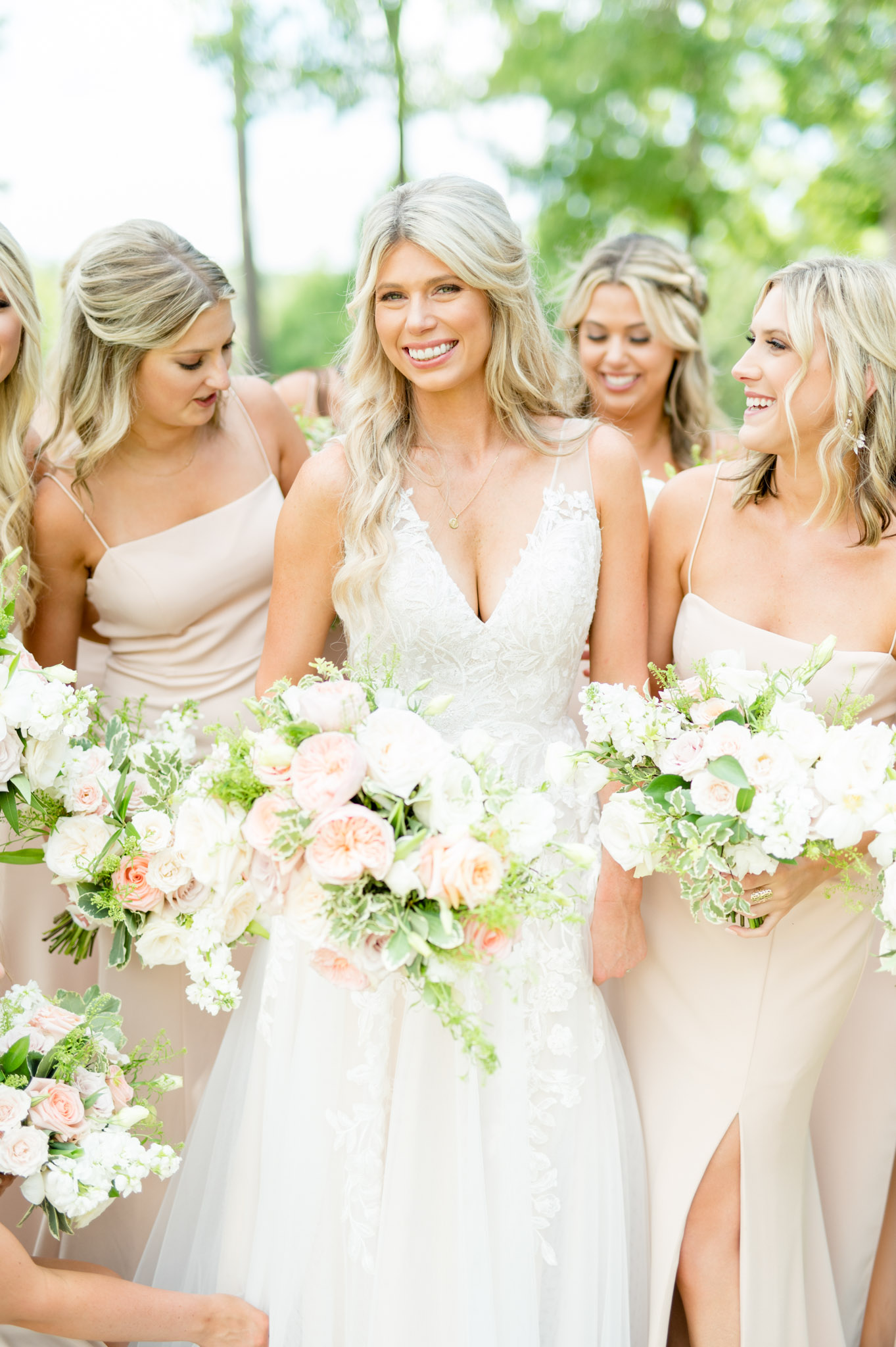 Bride smiles at camera while bridesmaids laugh.