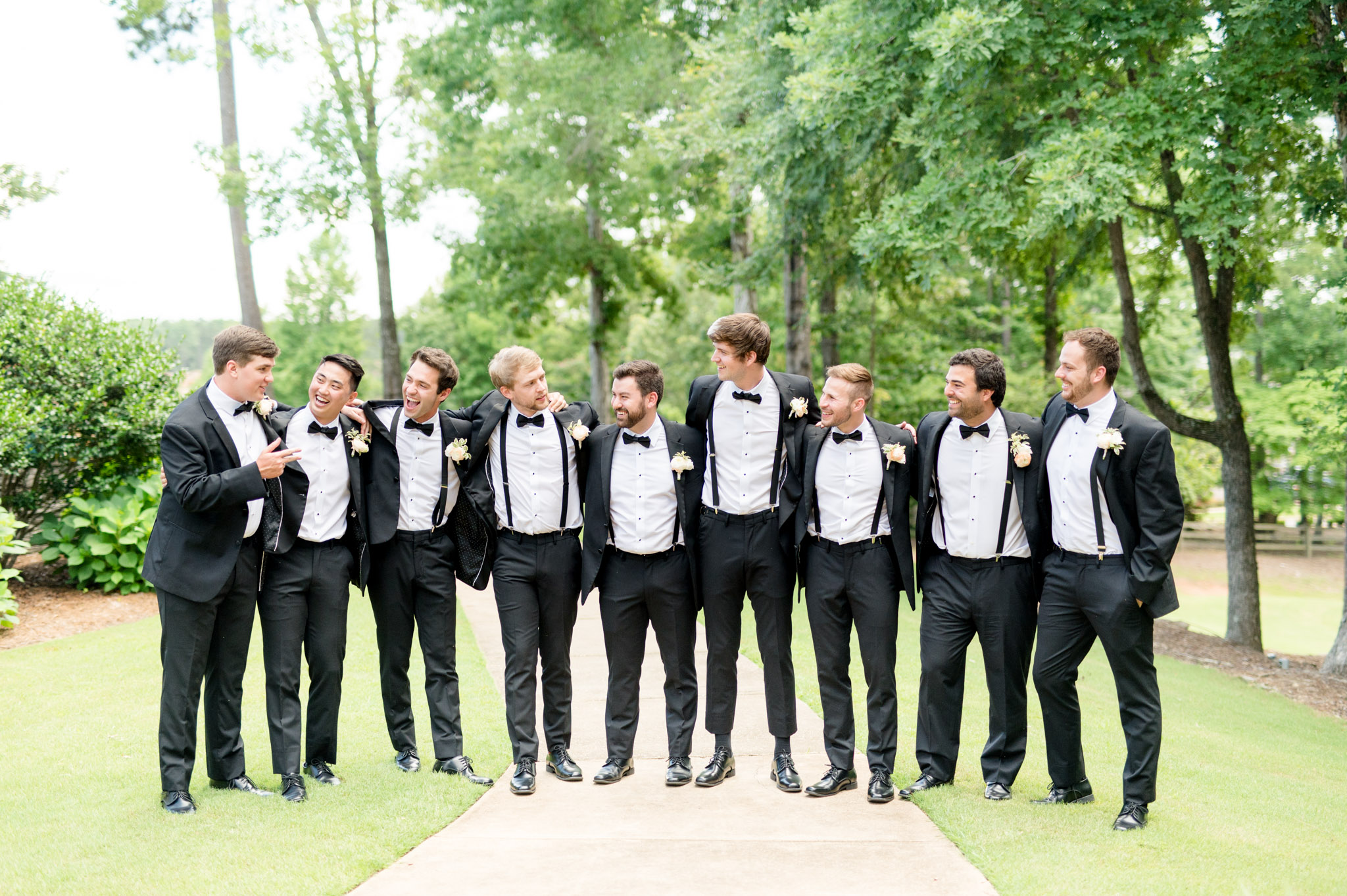 Groom and groomsmen laugh while hanging out.