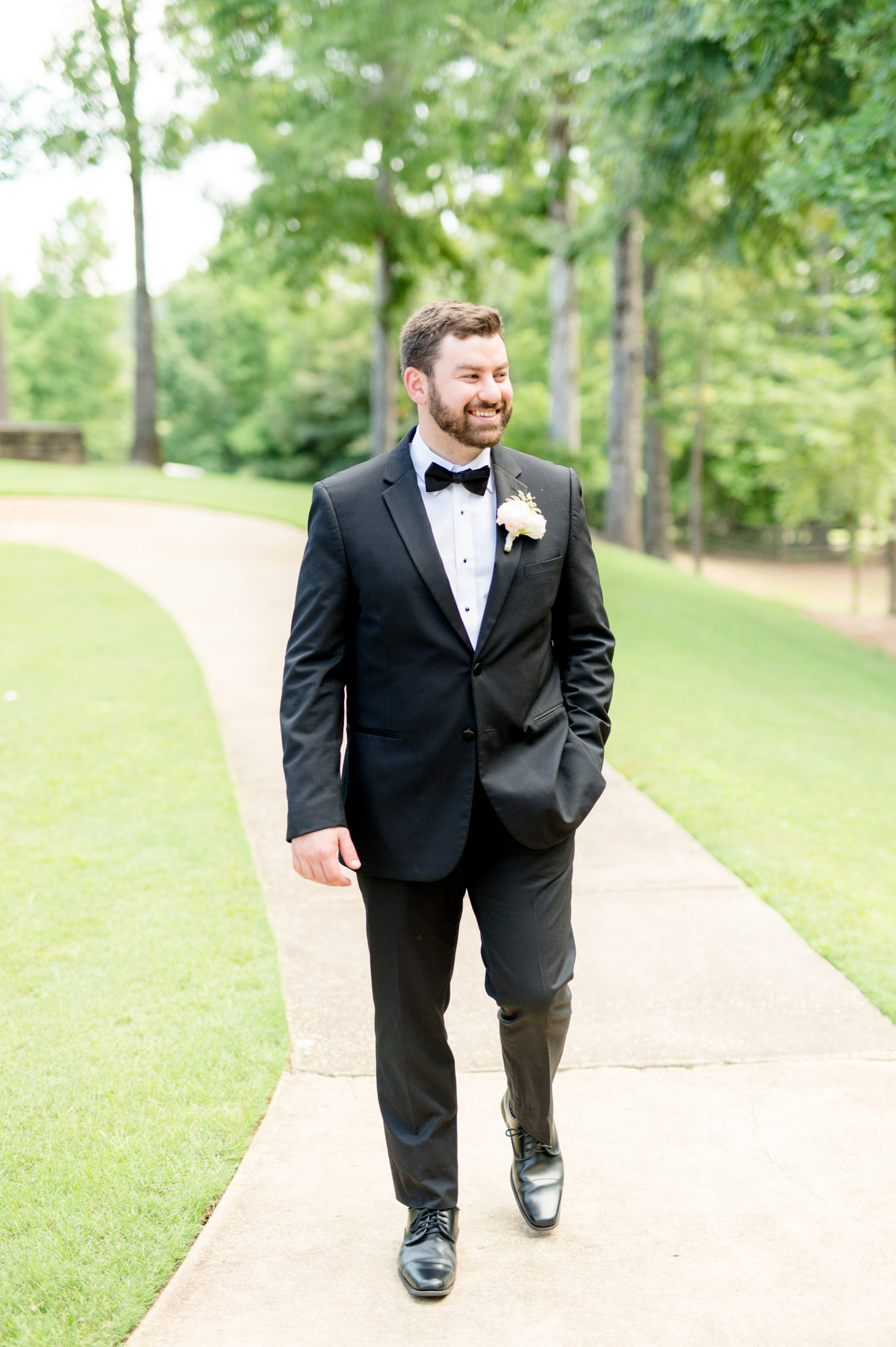 Groom walks down path and laughs.
