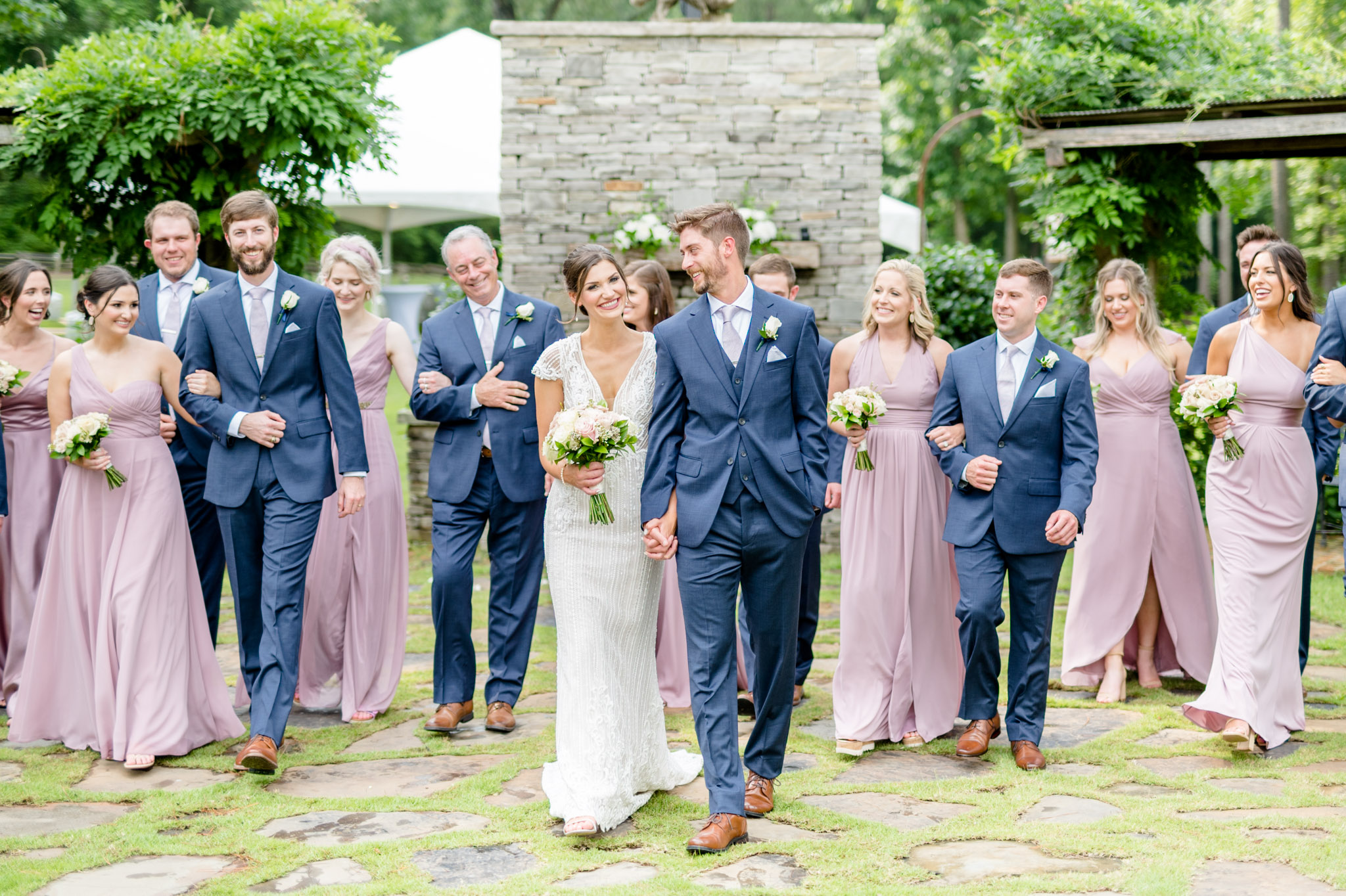 Bride and groom walk and talk with wedding party.