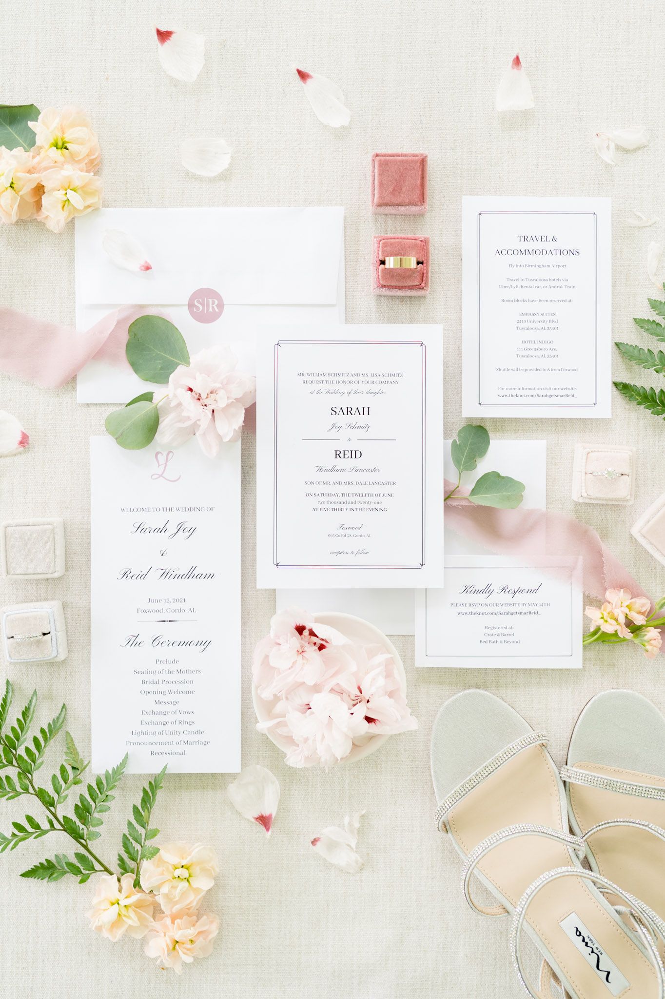 Wedding invitation suite and flowers sit on cream backdrop.