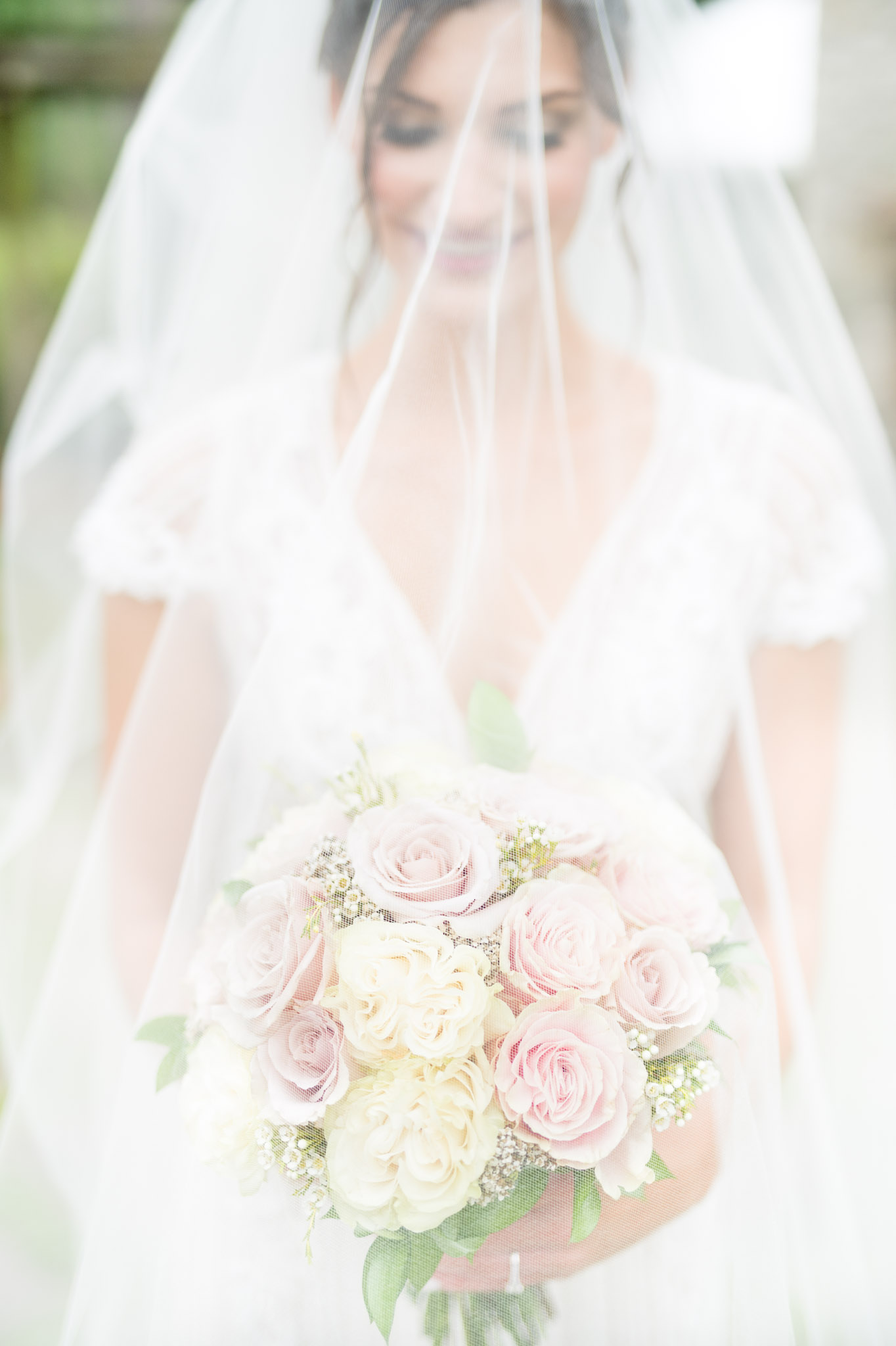 Bride holds bouquet under veil.