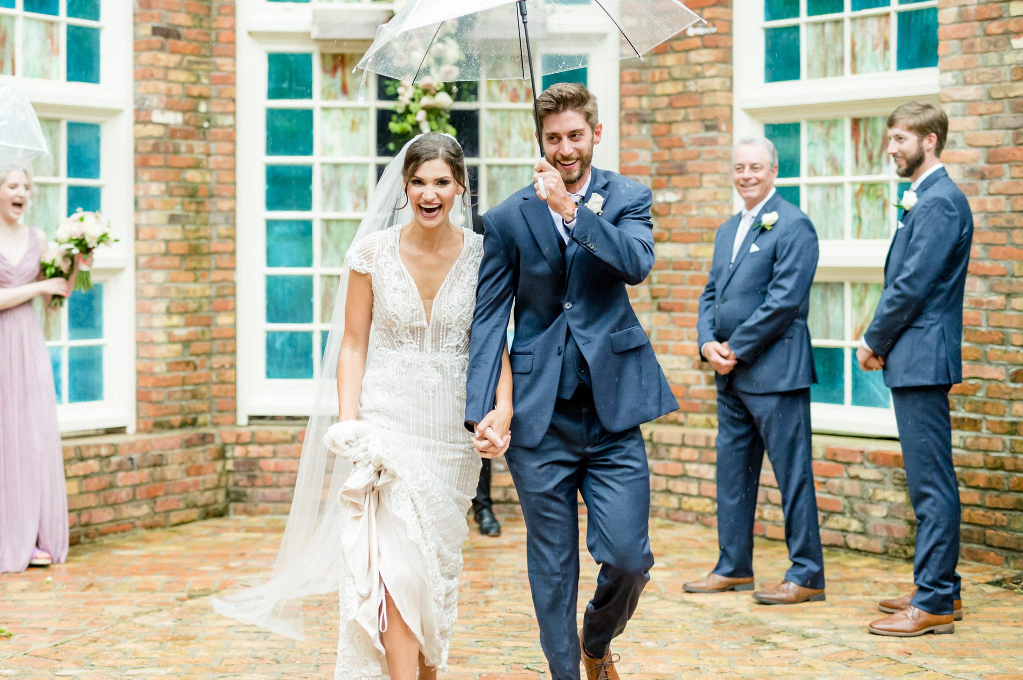 Bride and groom walk back down aisle in rain.