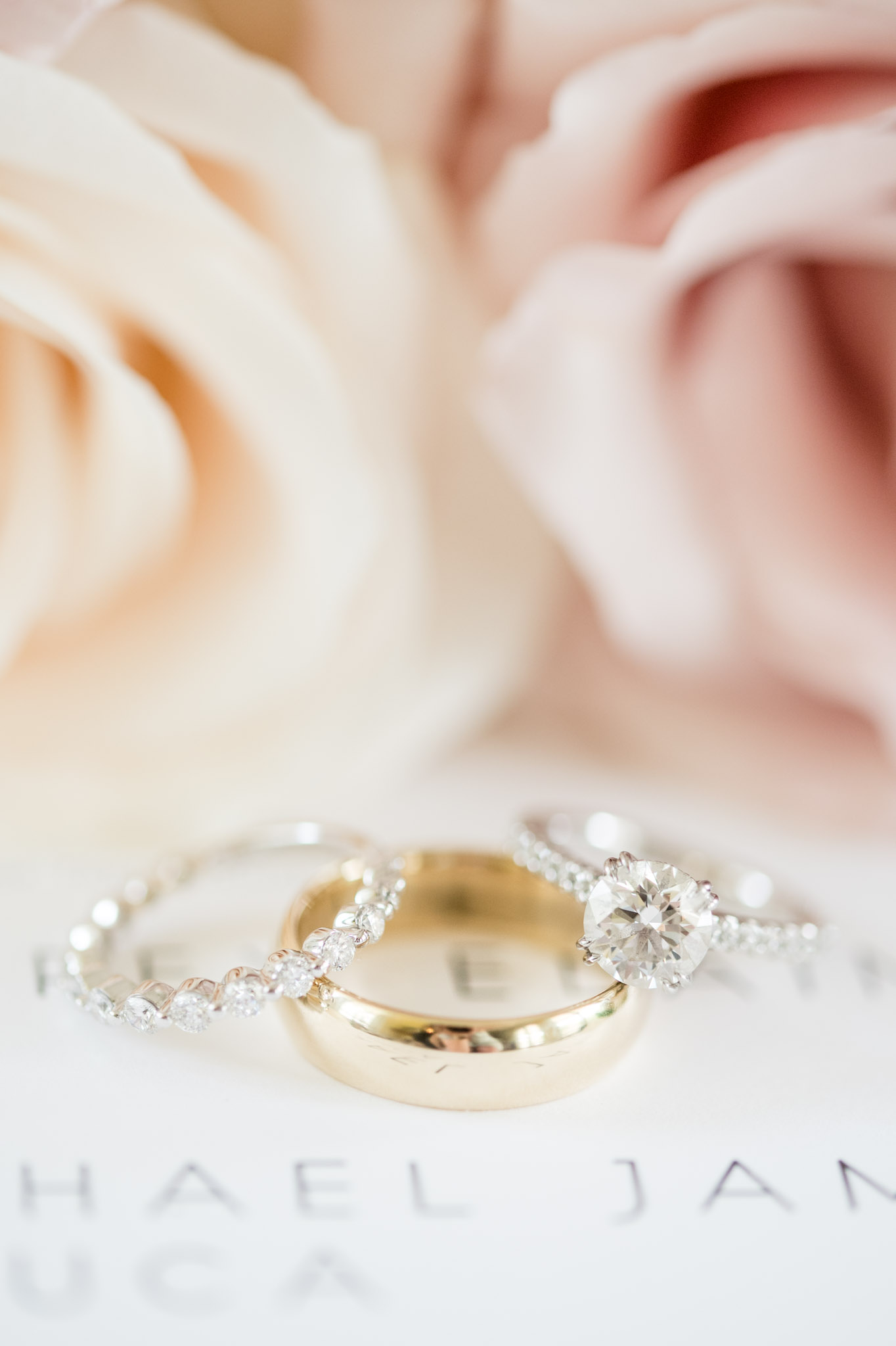 Wedding rings sit on wedding invitations.
