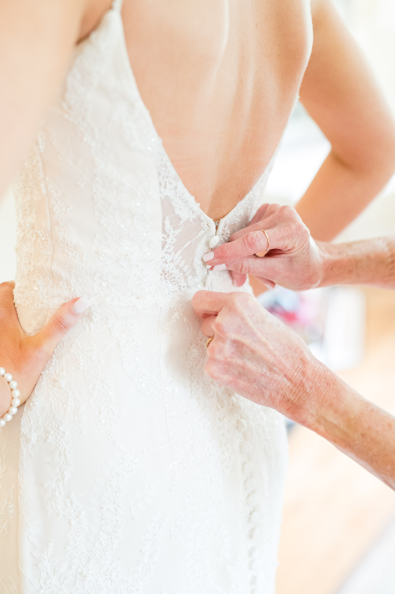 Mom buttons up bride's dress.