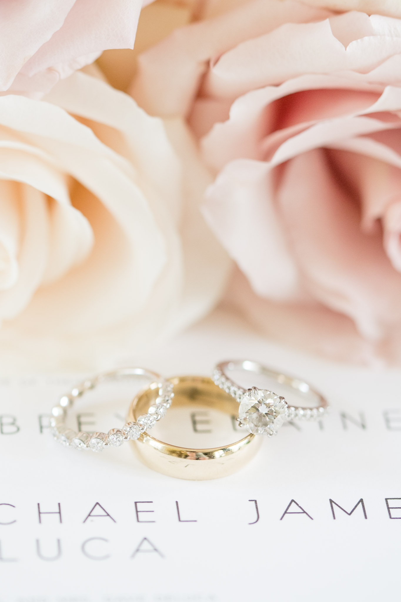 Bride and groom wedding rings with flowers and invitations.