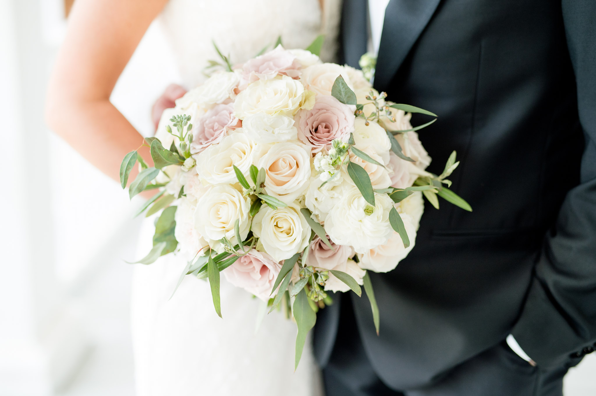 Bride holds white, cream, and pink flowers.