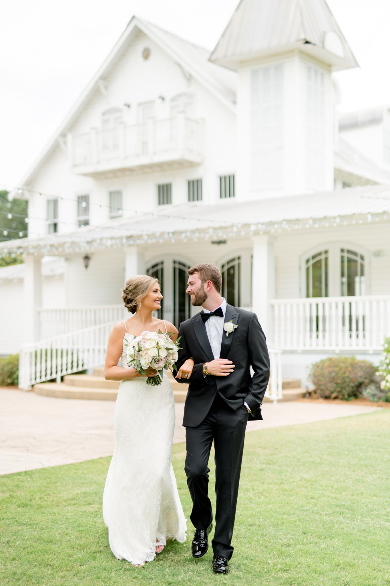 Bride and groom smile while walking across The Sonnet House lawn.