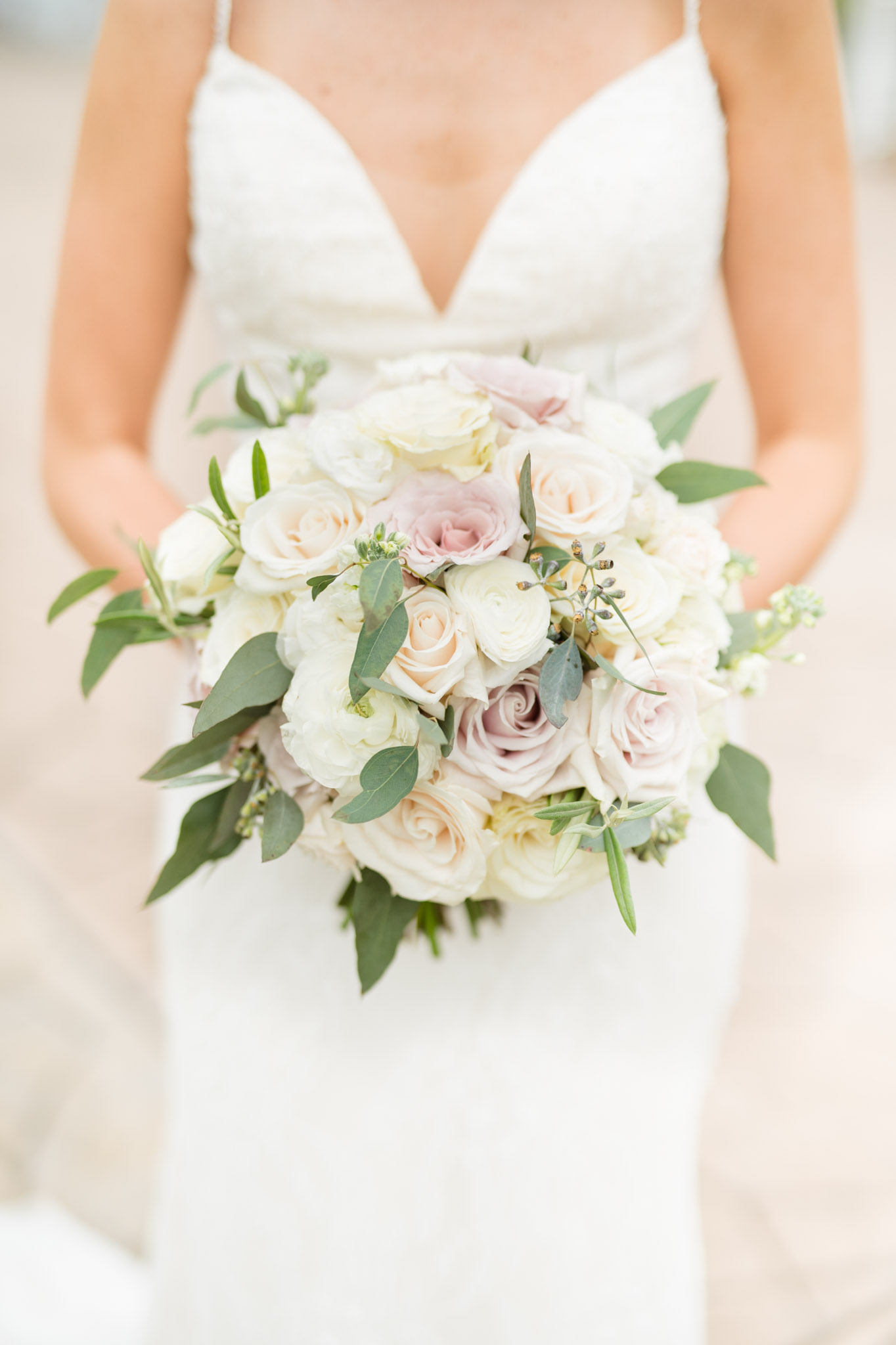 Bride holds white and cream roses.