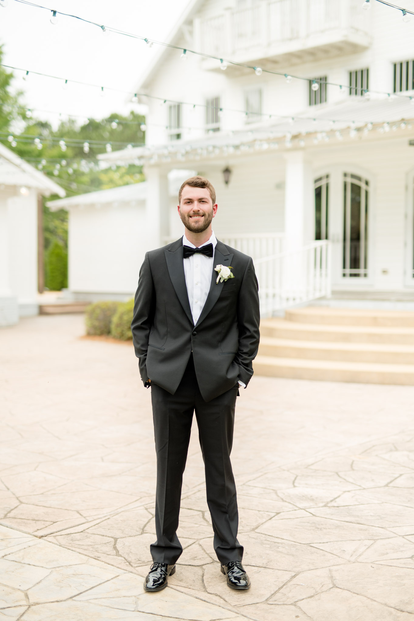 Groom stands and smiles at camera.