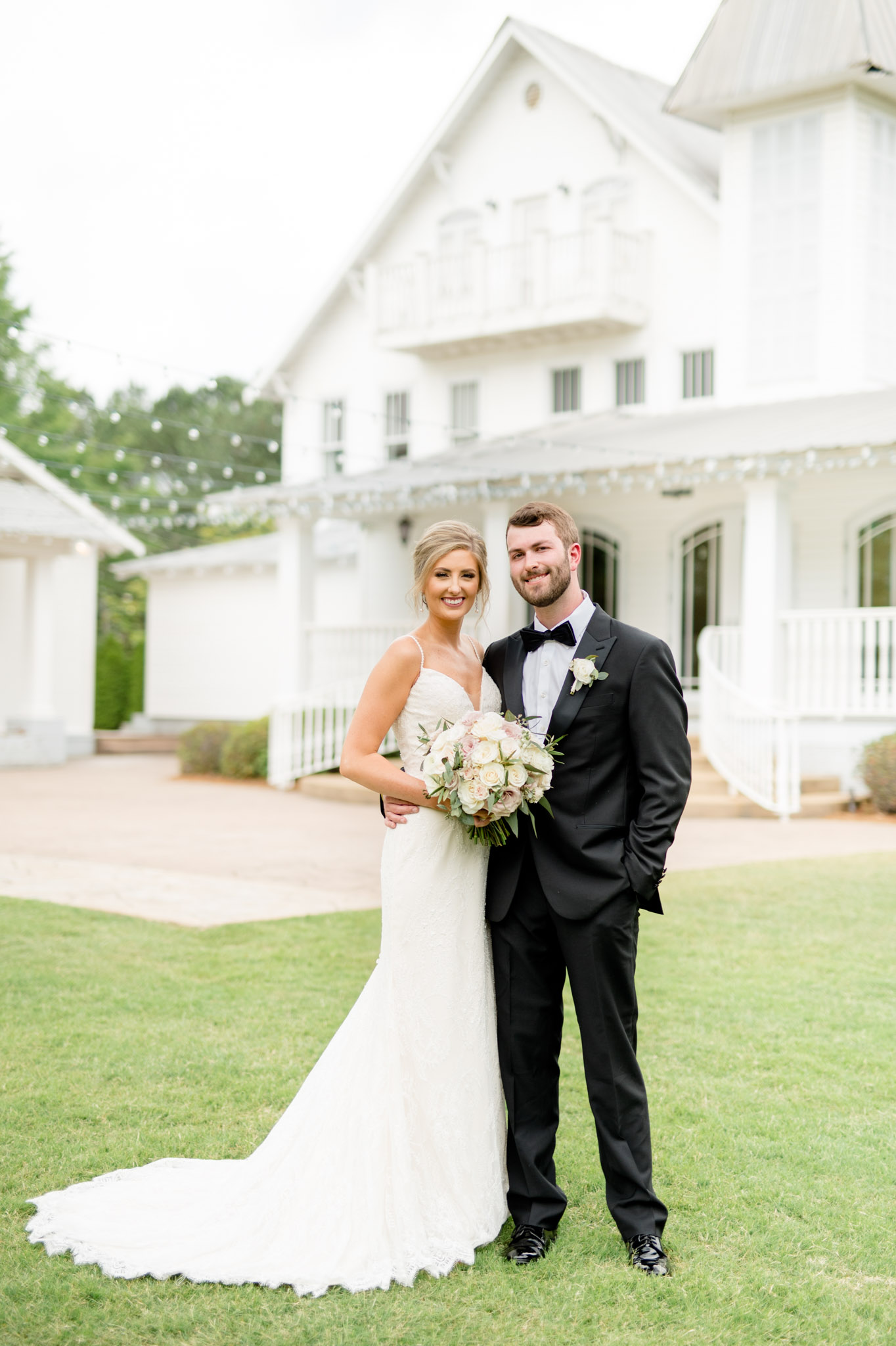 Bride and groom smile at camera from lawn.