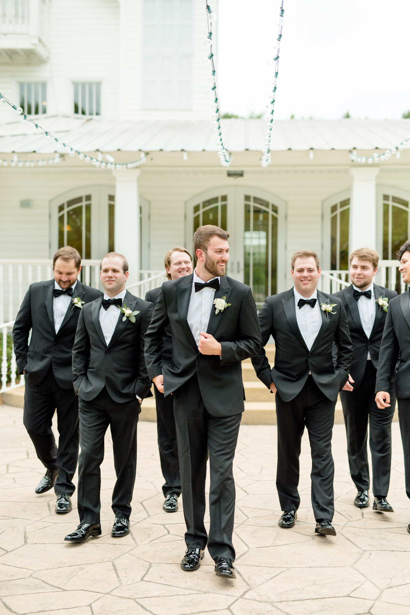 Groom walks with groomsmen and smiles.