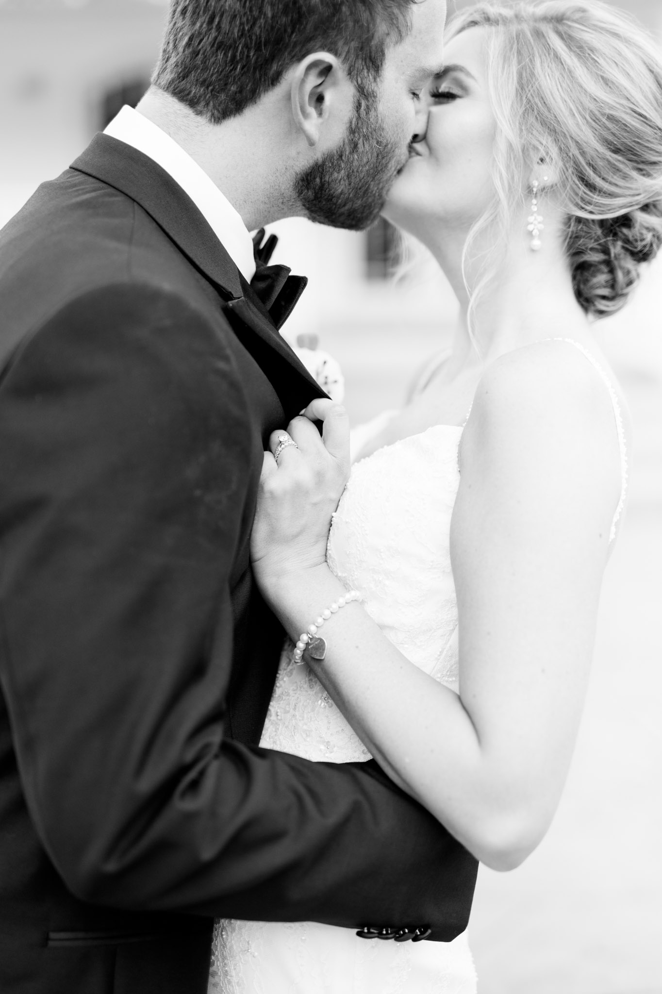 Bride and groom kiss with closeup of ring.