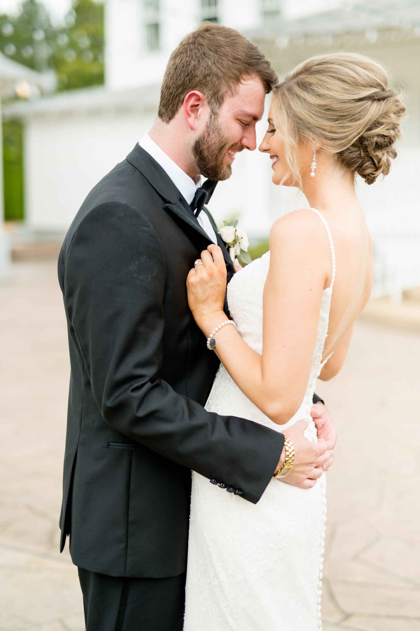Bride holds groom's lapels as they cuddle.