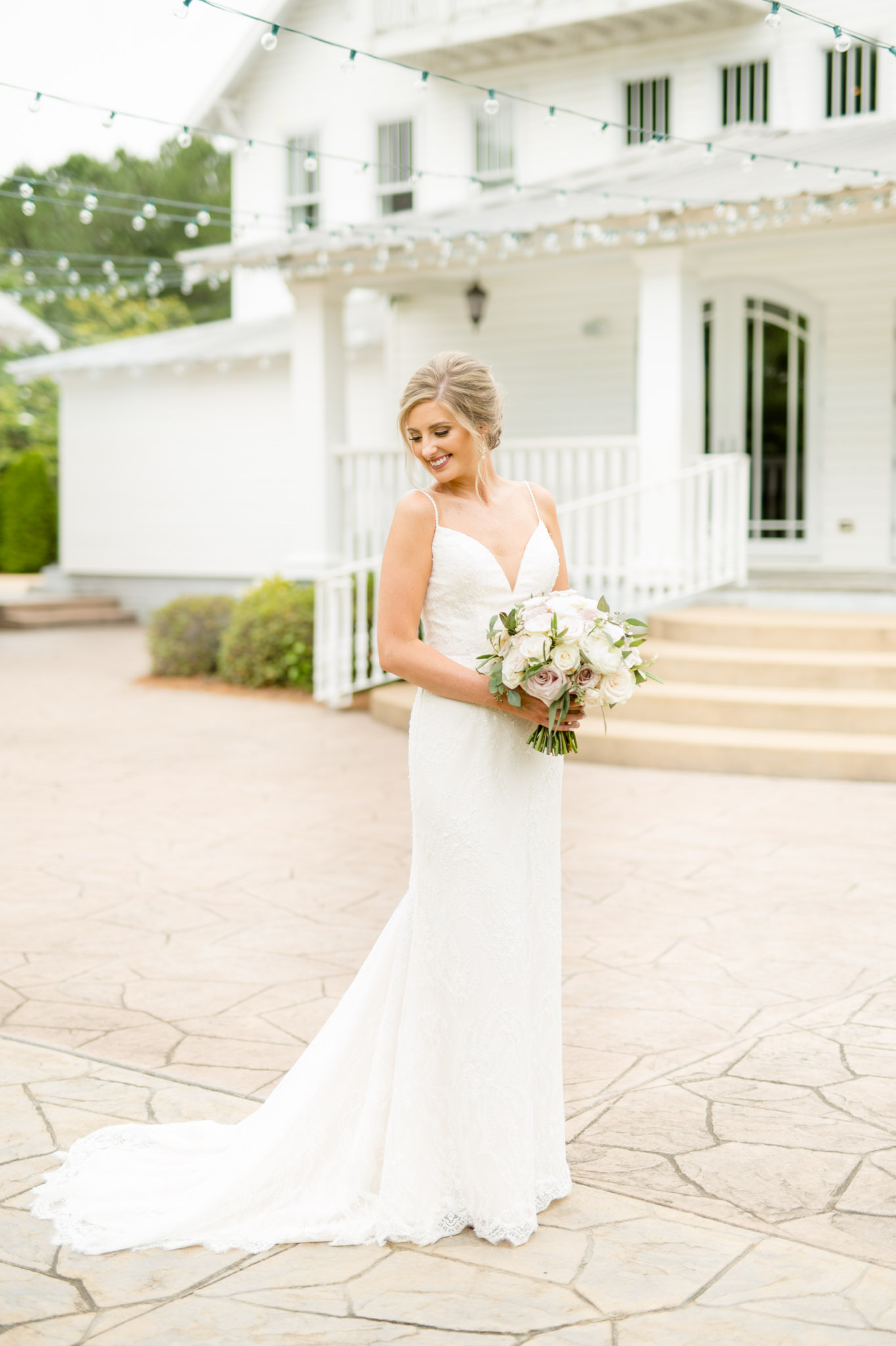 Bride looks down shoulder while holding flowers.