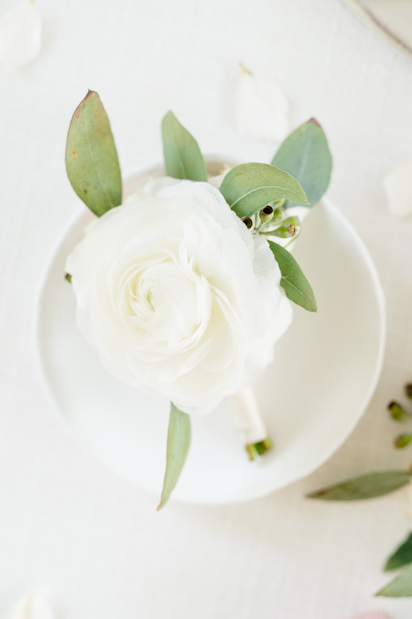Groom's boutonniere sits on white dish.
