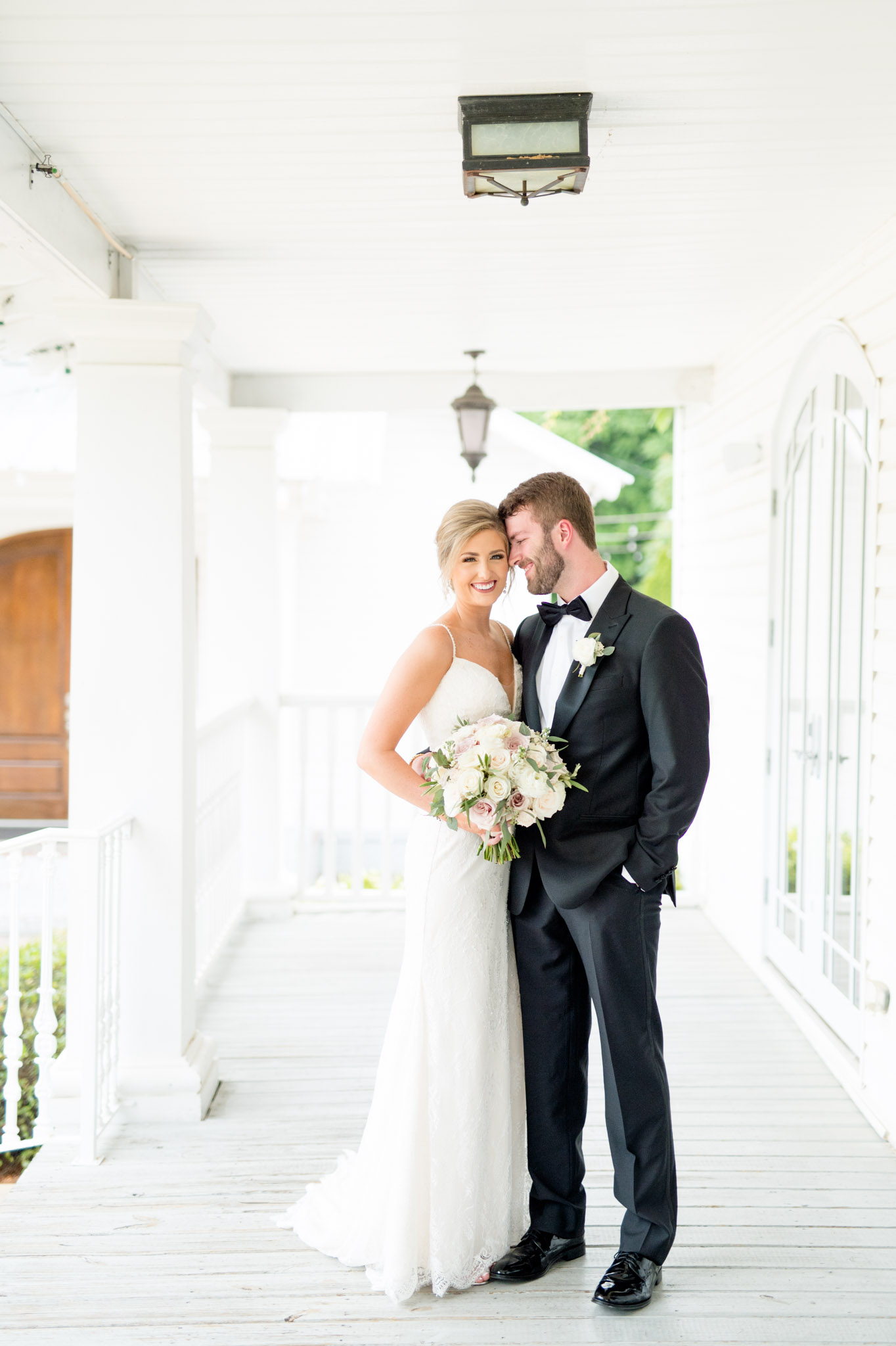 Groom cuddles bride as she smiles at camera.