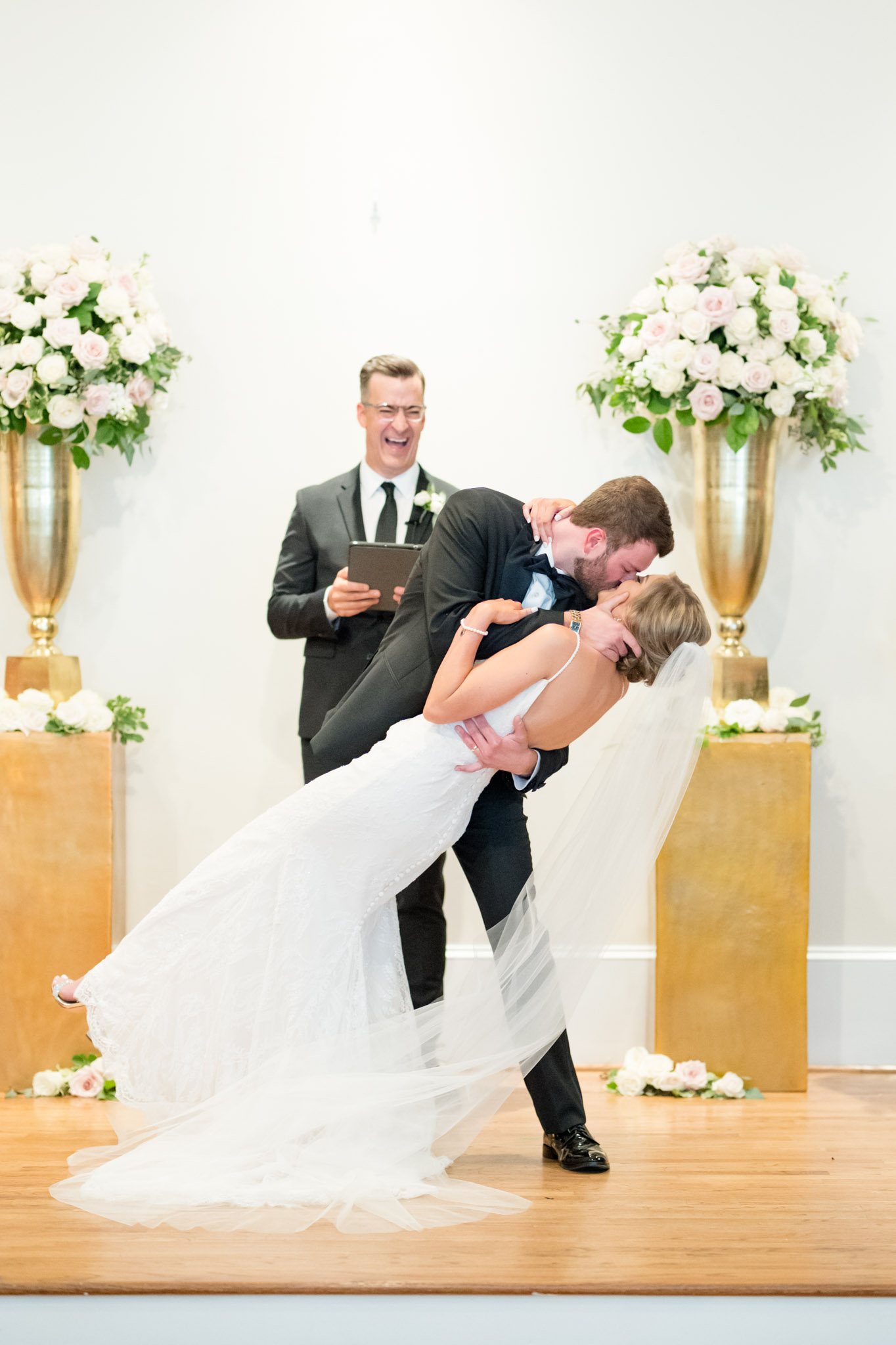 Groom dips bride back for kiss at ceremony.