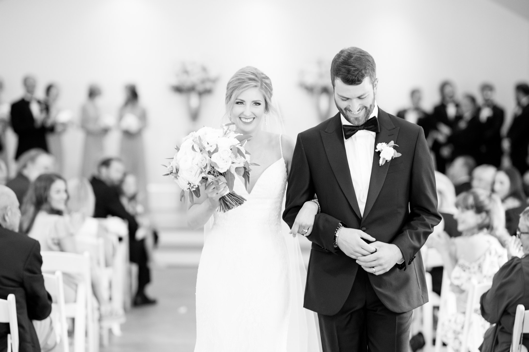Bride and groom smile as they walk up aisle.