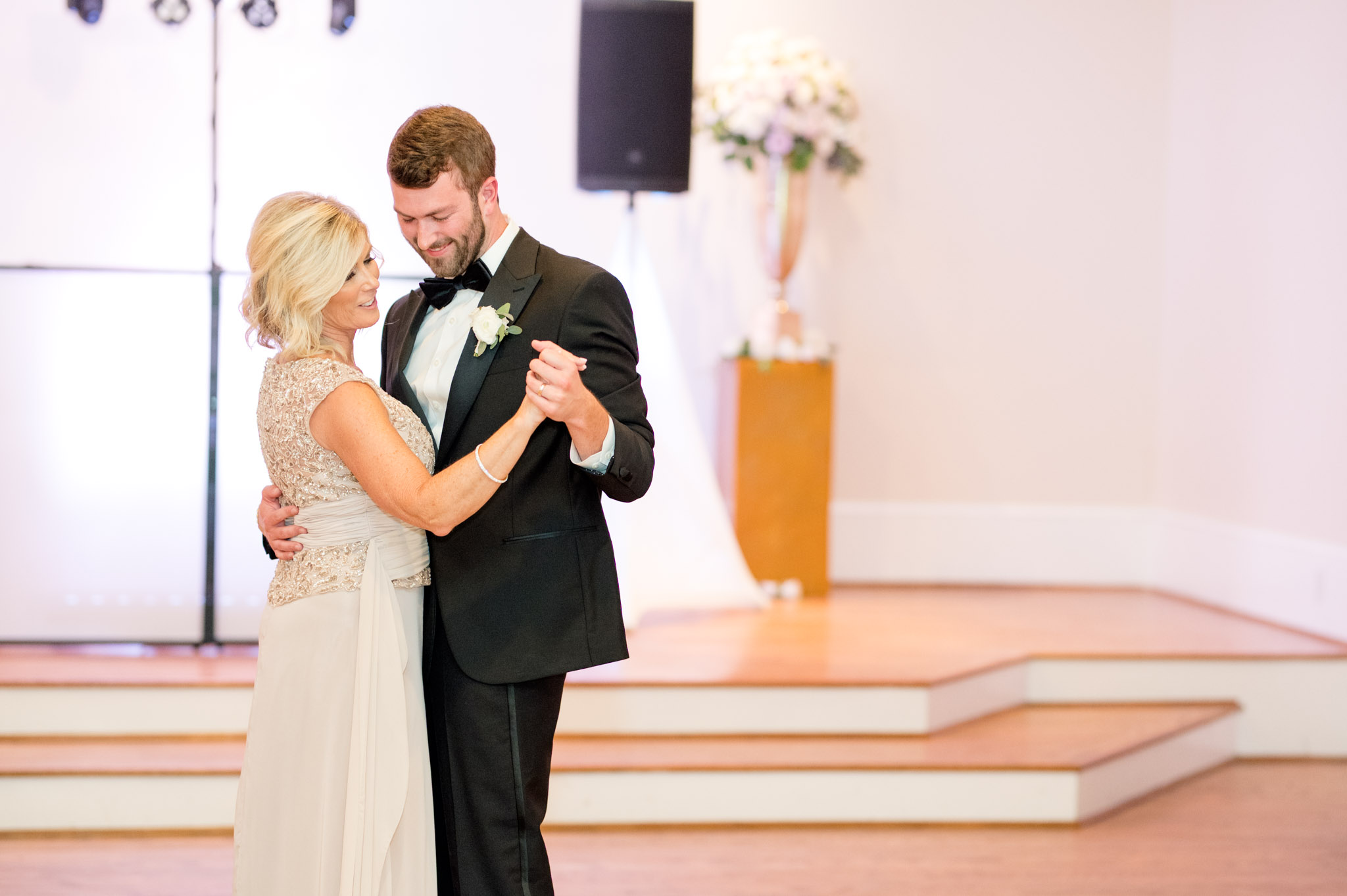 Groom and his mother laugh while dancing.