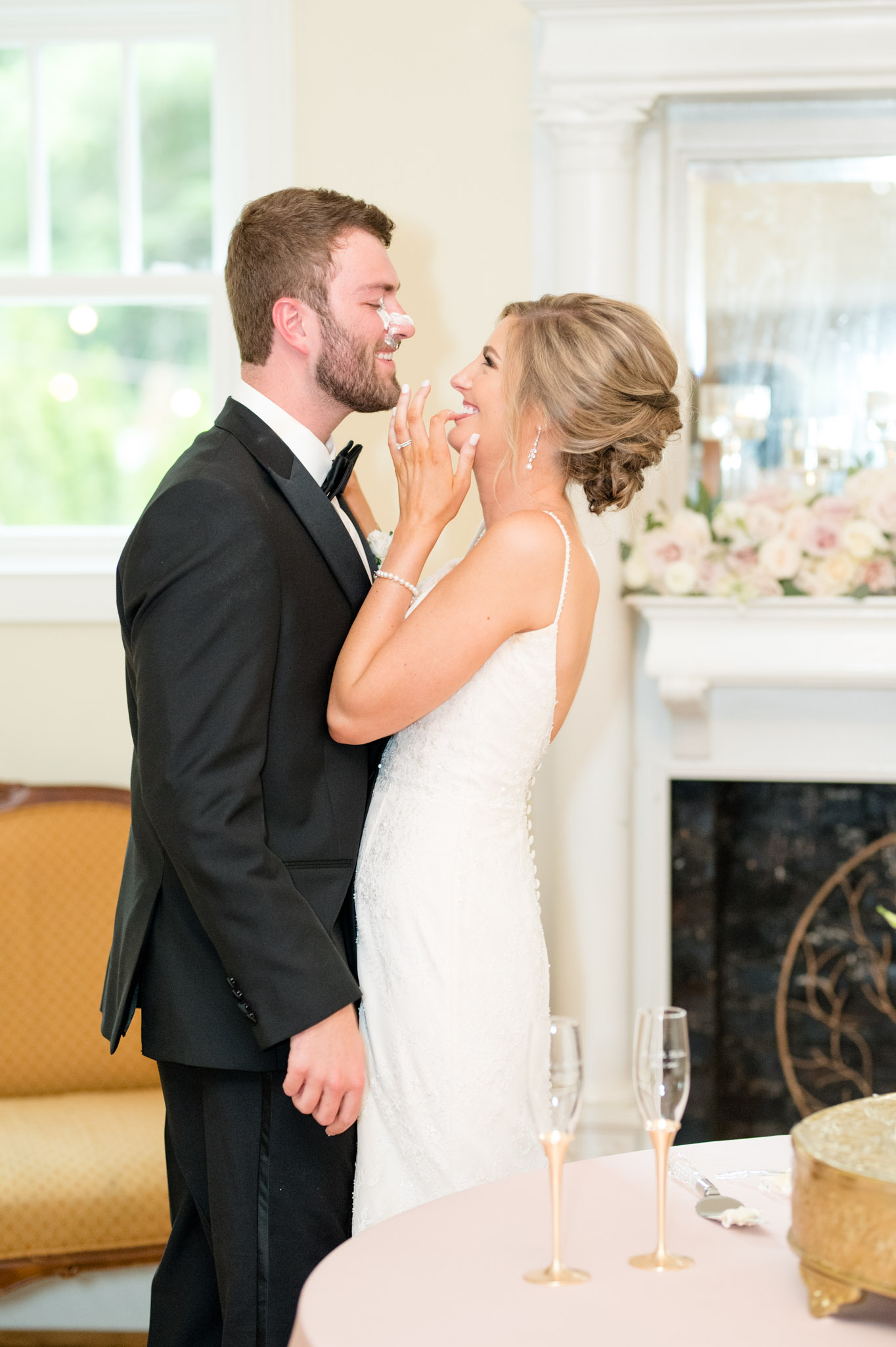 Bride laughs as she smears icing on groom's nose.