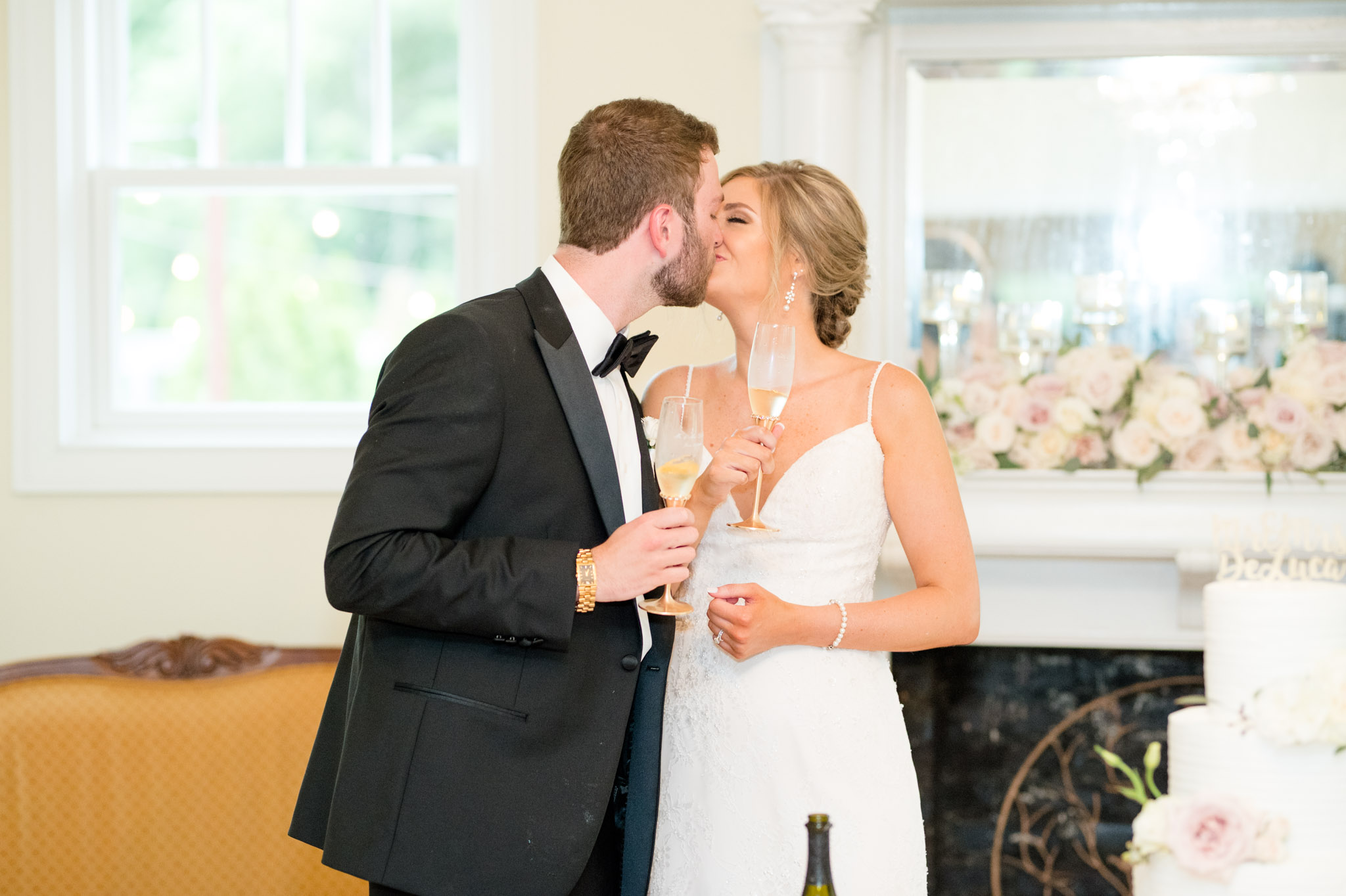 Bride and groom kiss while sharing a toast.