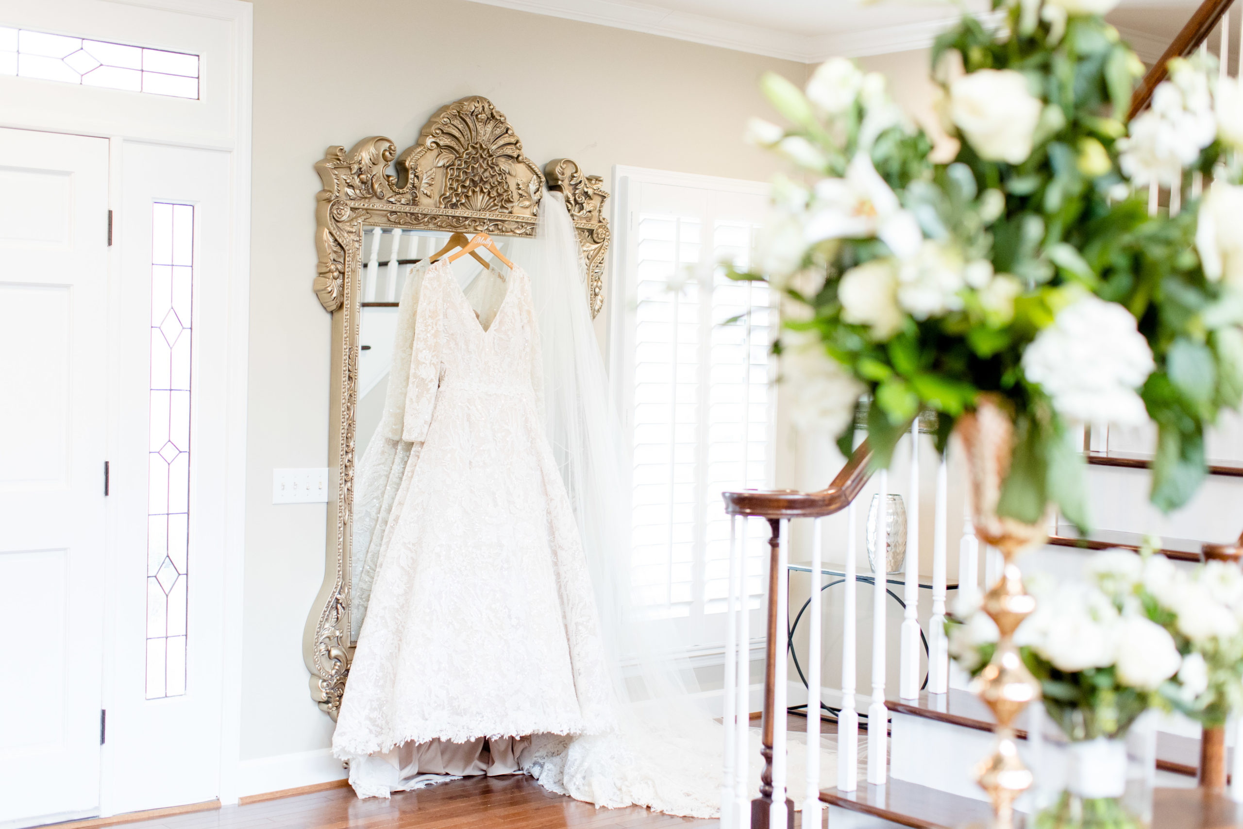 Bride's dress hangs on mirror.