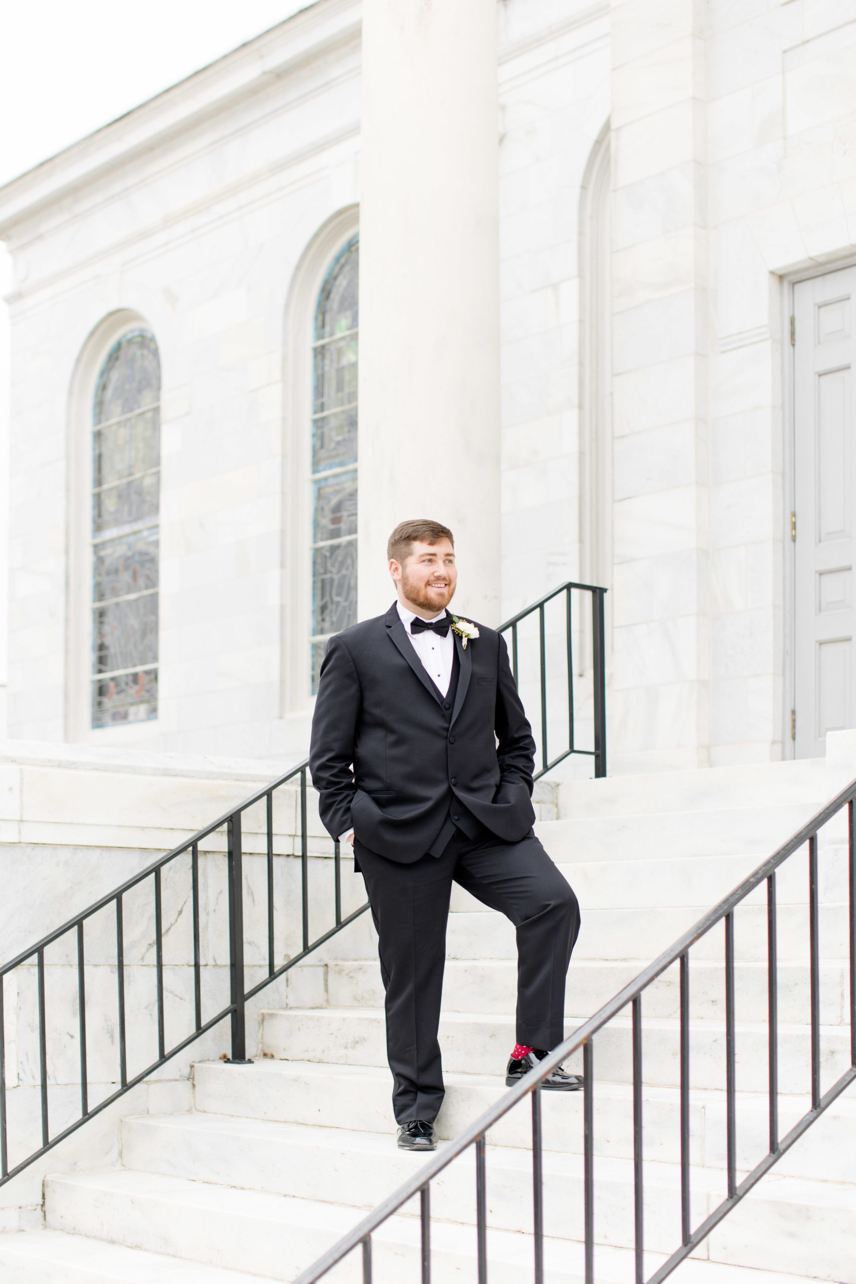 Groom stands on steps and smiles.