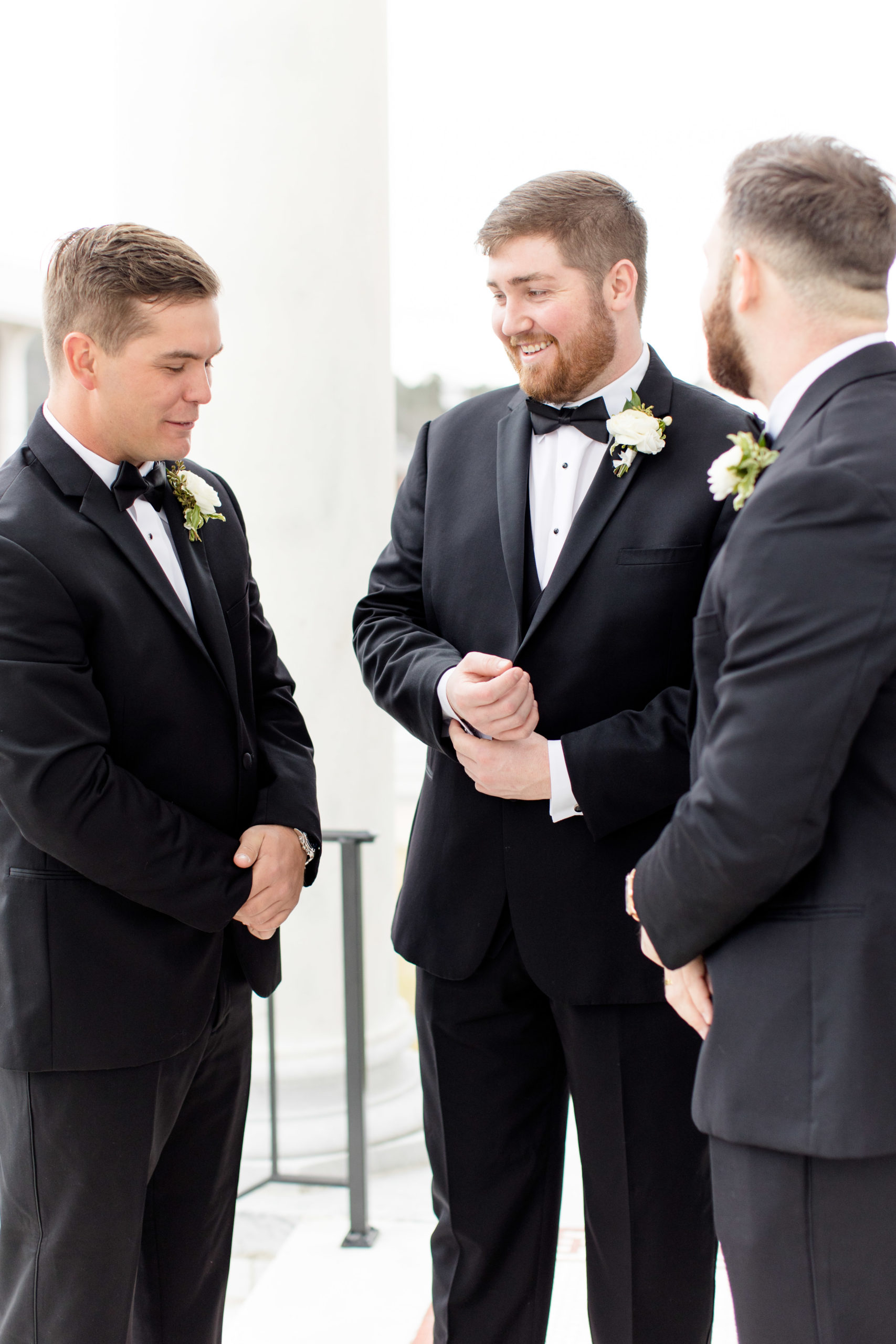 Groom laughs while getting ready with groomsment.