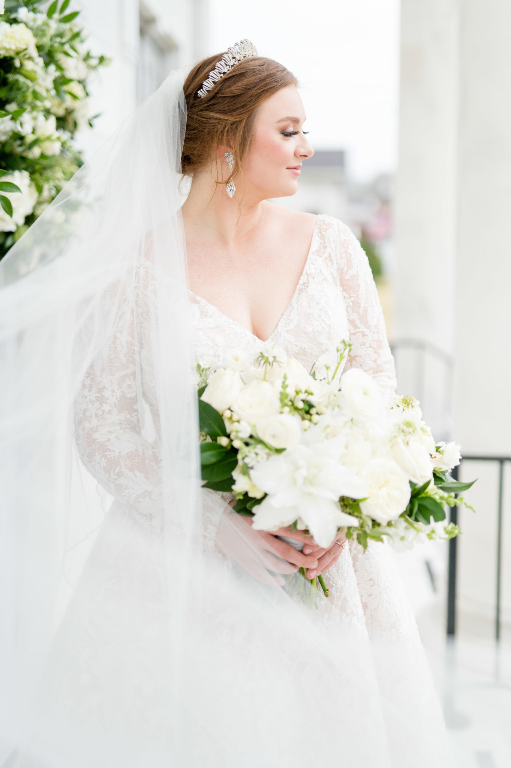 Bride looks over shoulder as veil blows in wind.