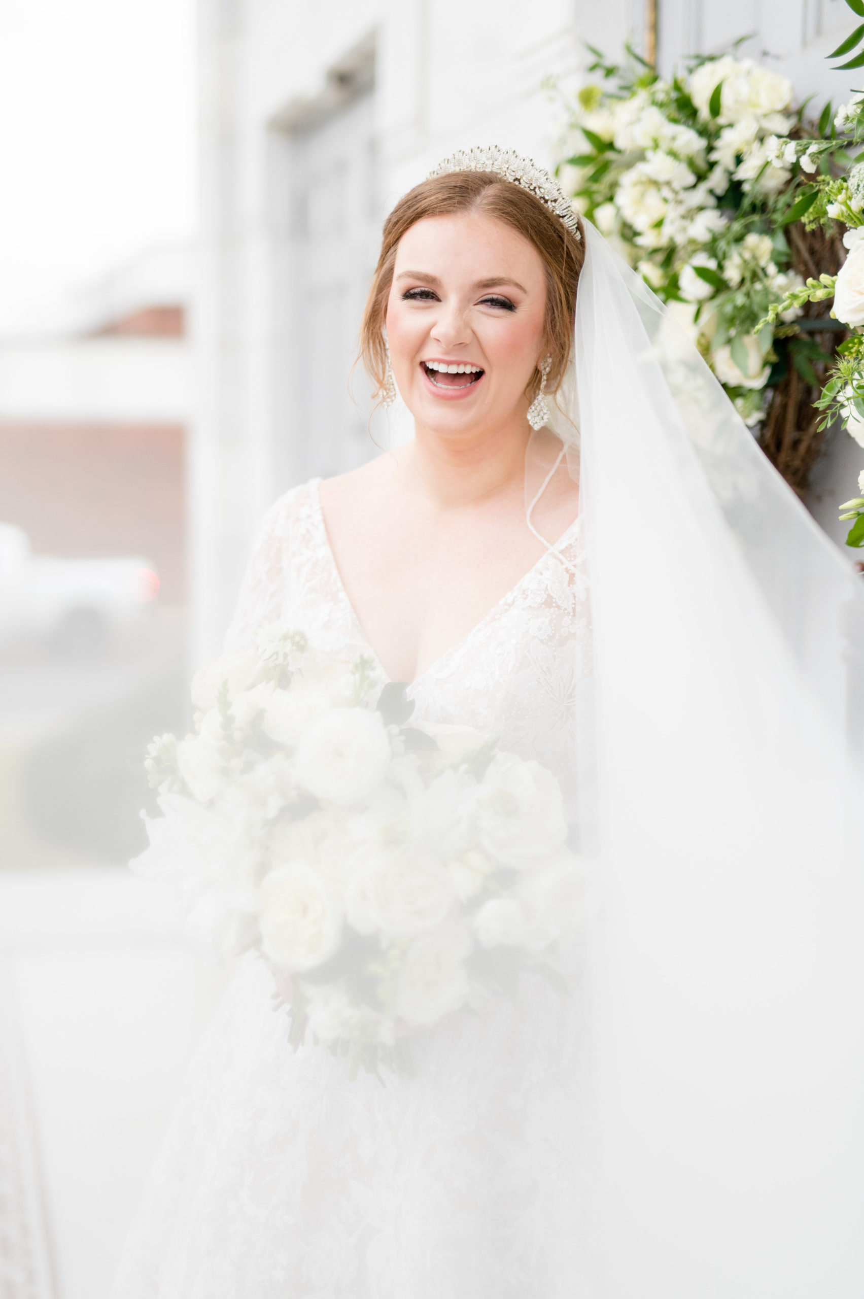 Bride laughs at camera while veil blows.