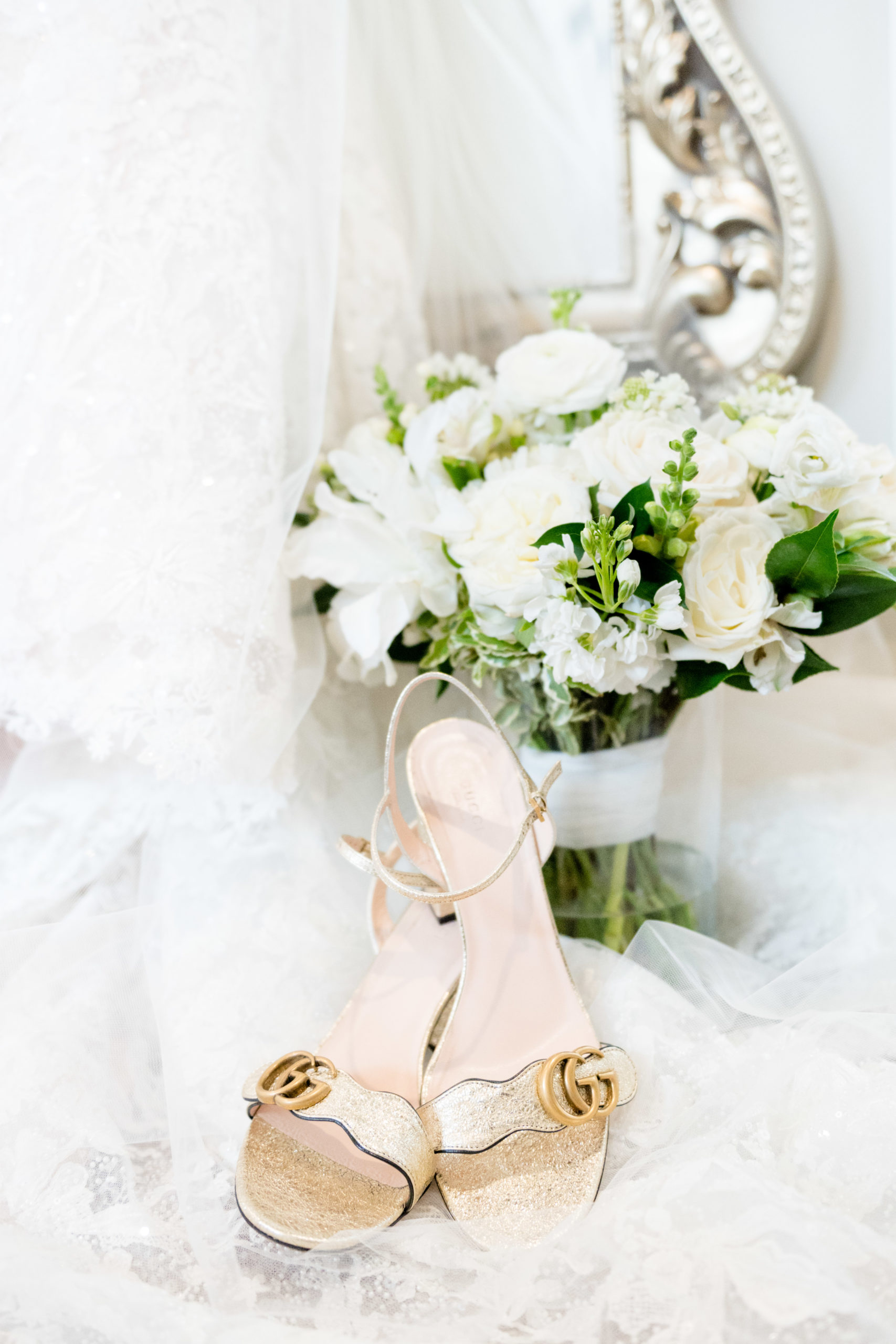Brides shoes sit with flowers and wedding dress.