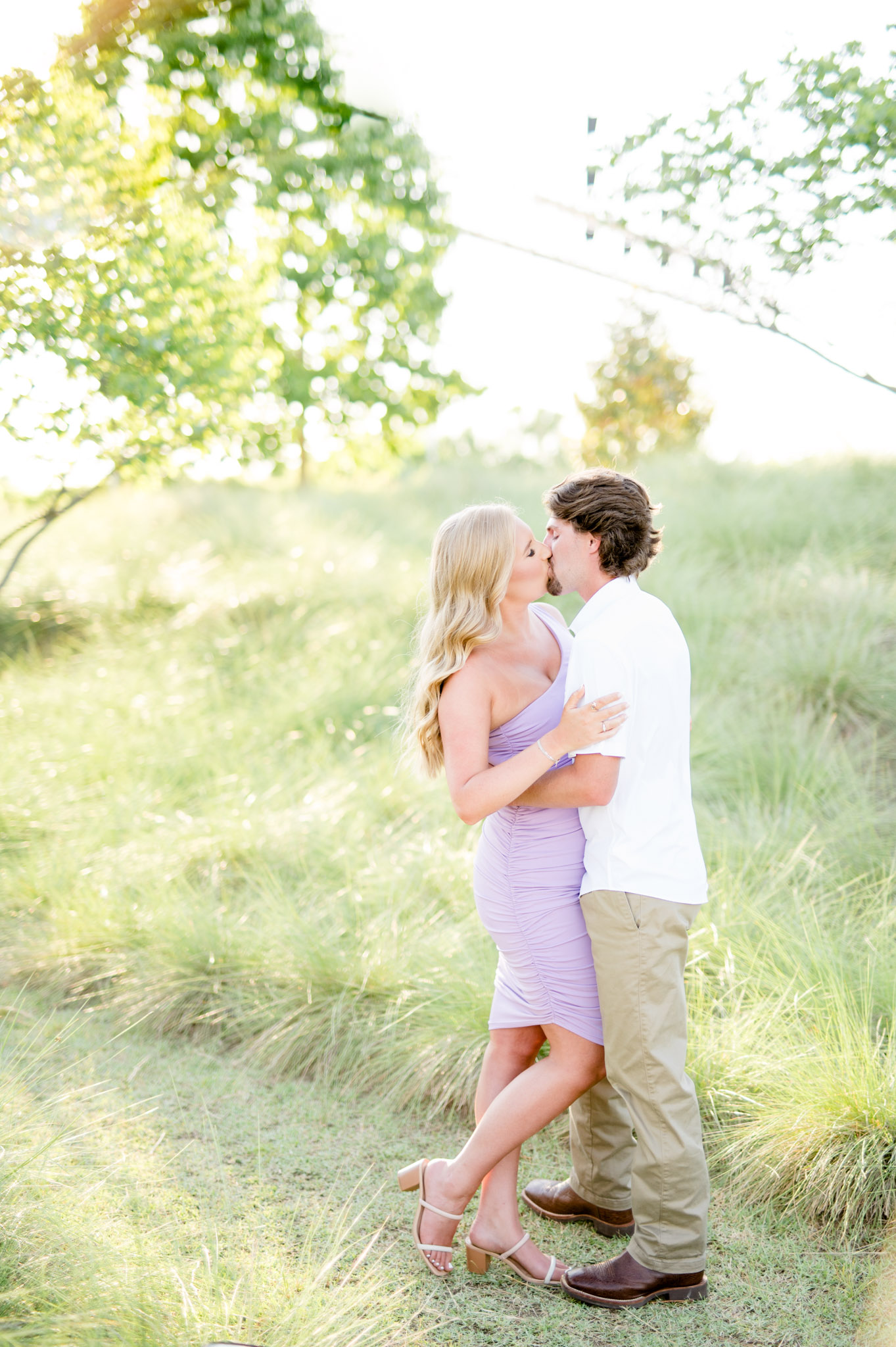 Man and woman kiss in field.