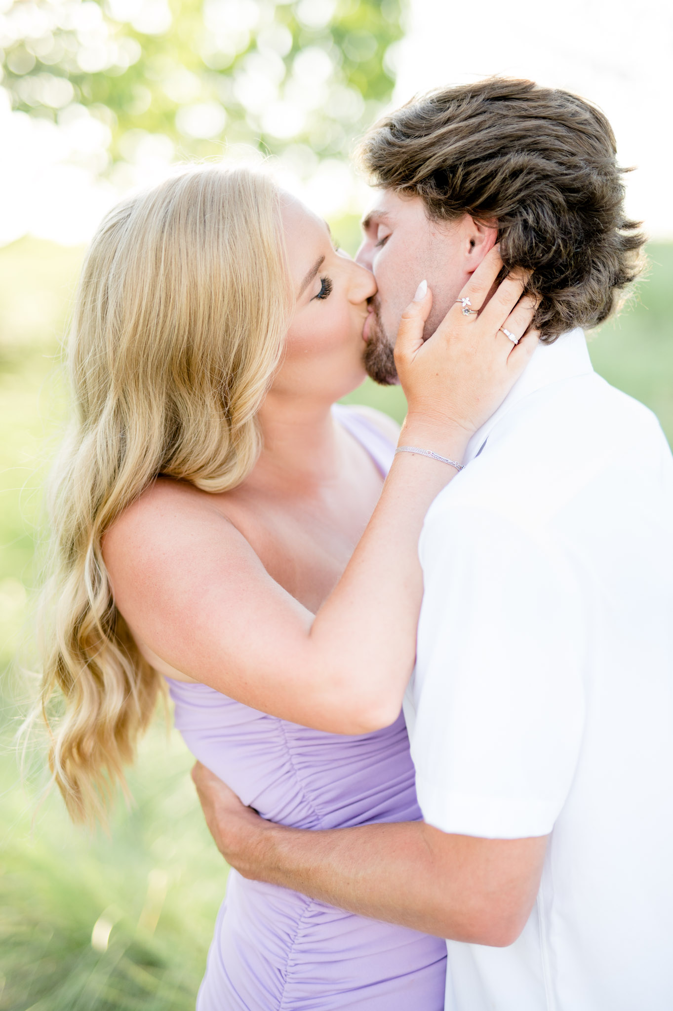 Couple kisses in field.