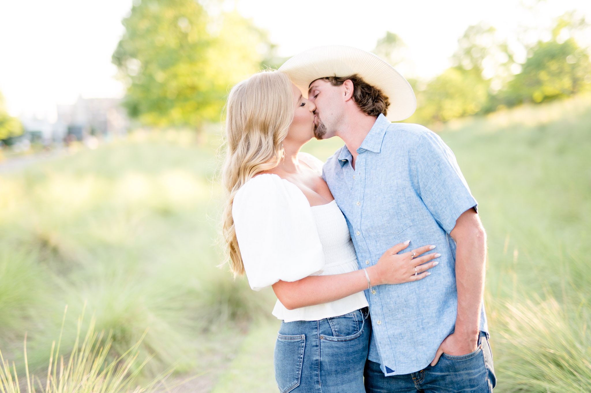 Man in cowboy hat kisses his fiance.