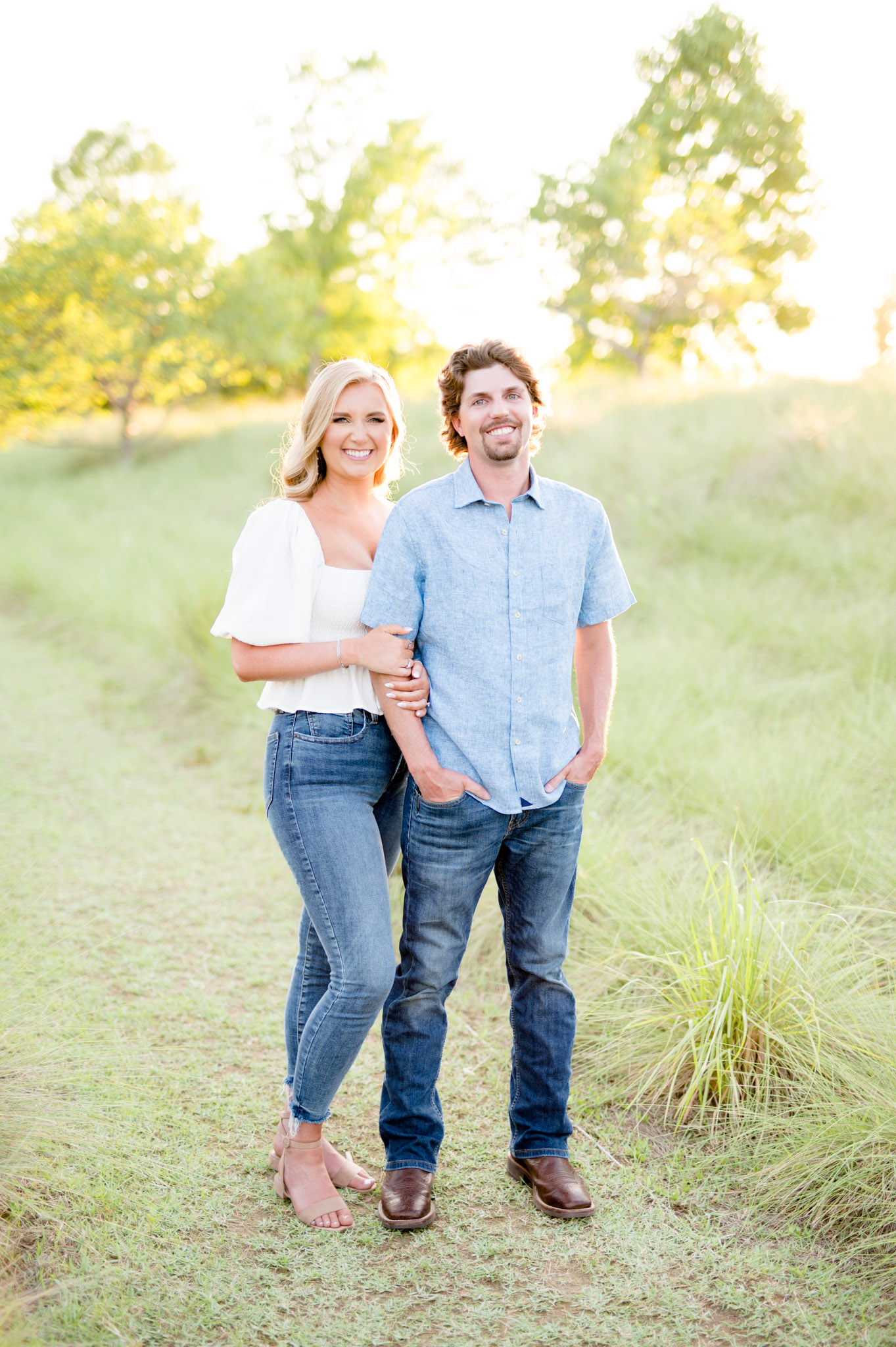 Couple stands in field and smile.