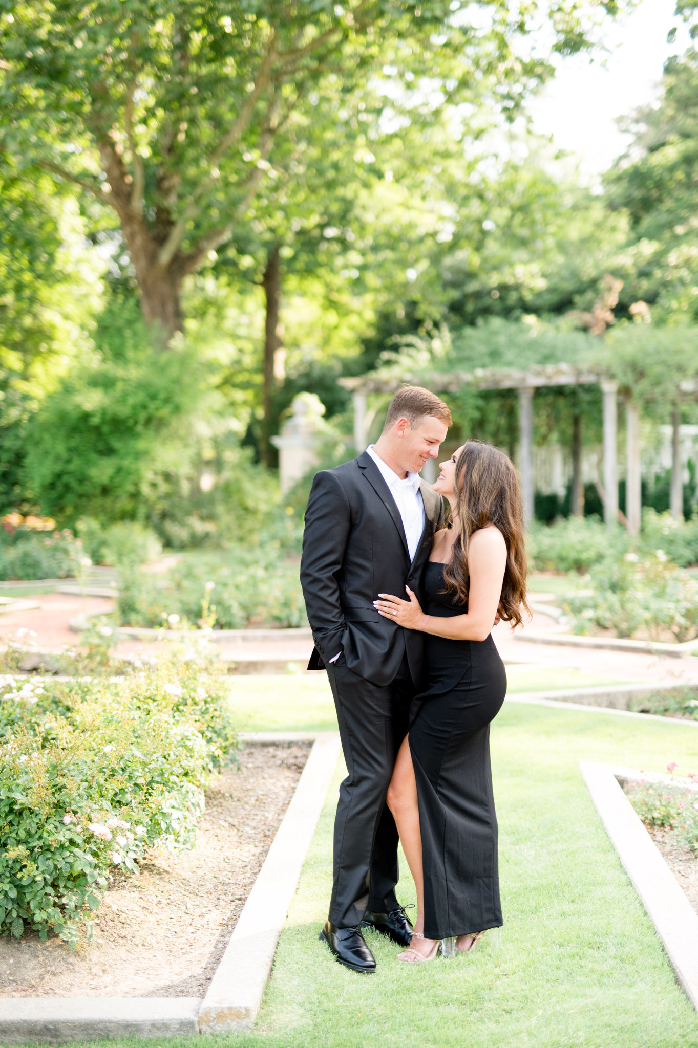 Couple looks at each other while standing in garden.