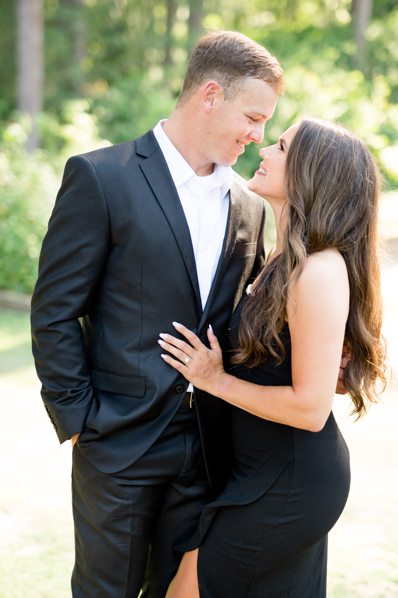 Couple looks at each other near trees.