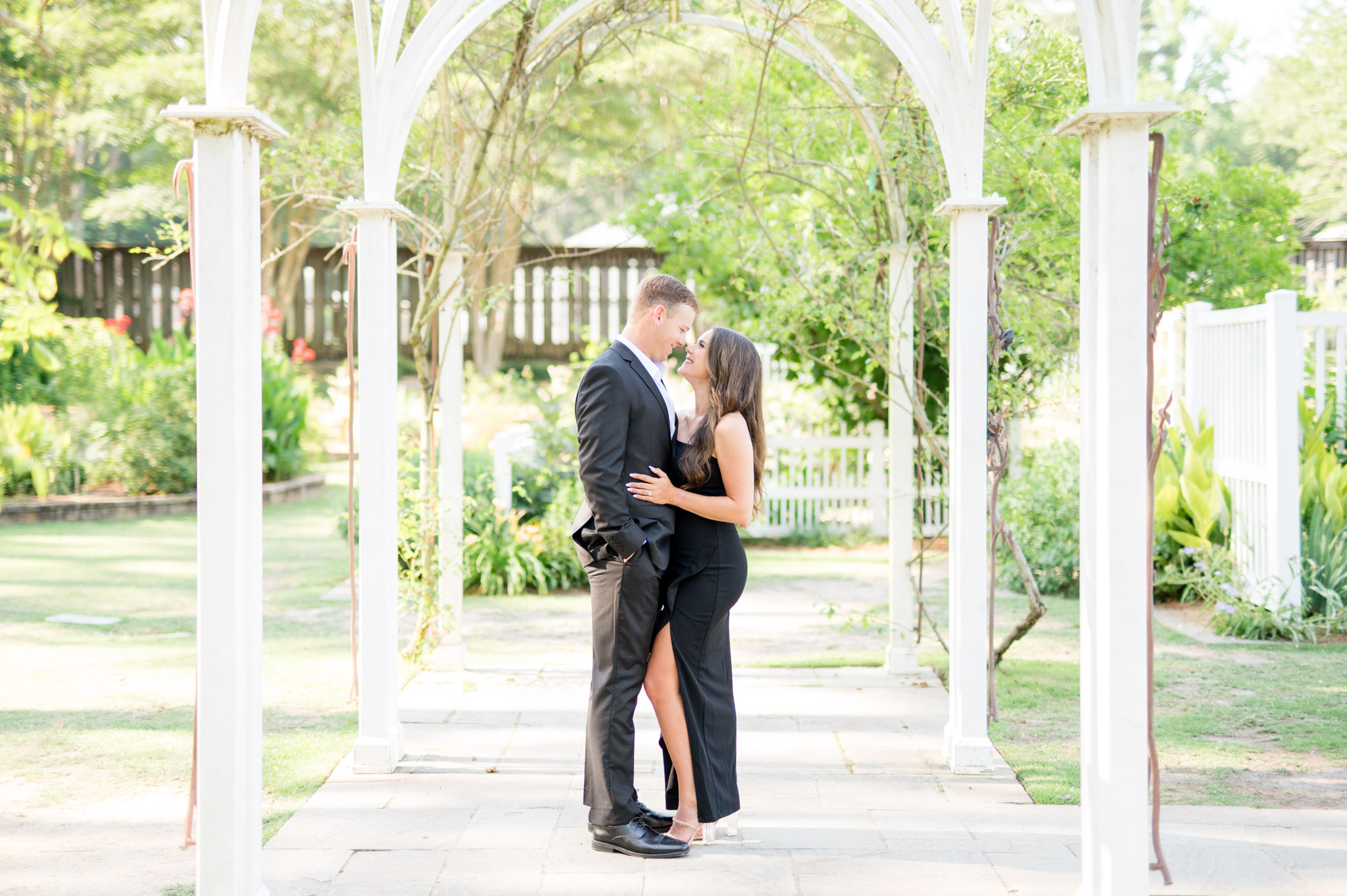 Couple snuggles under trellis.