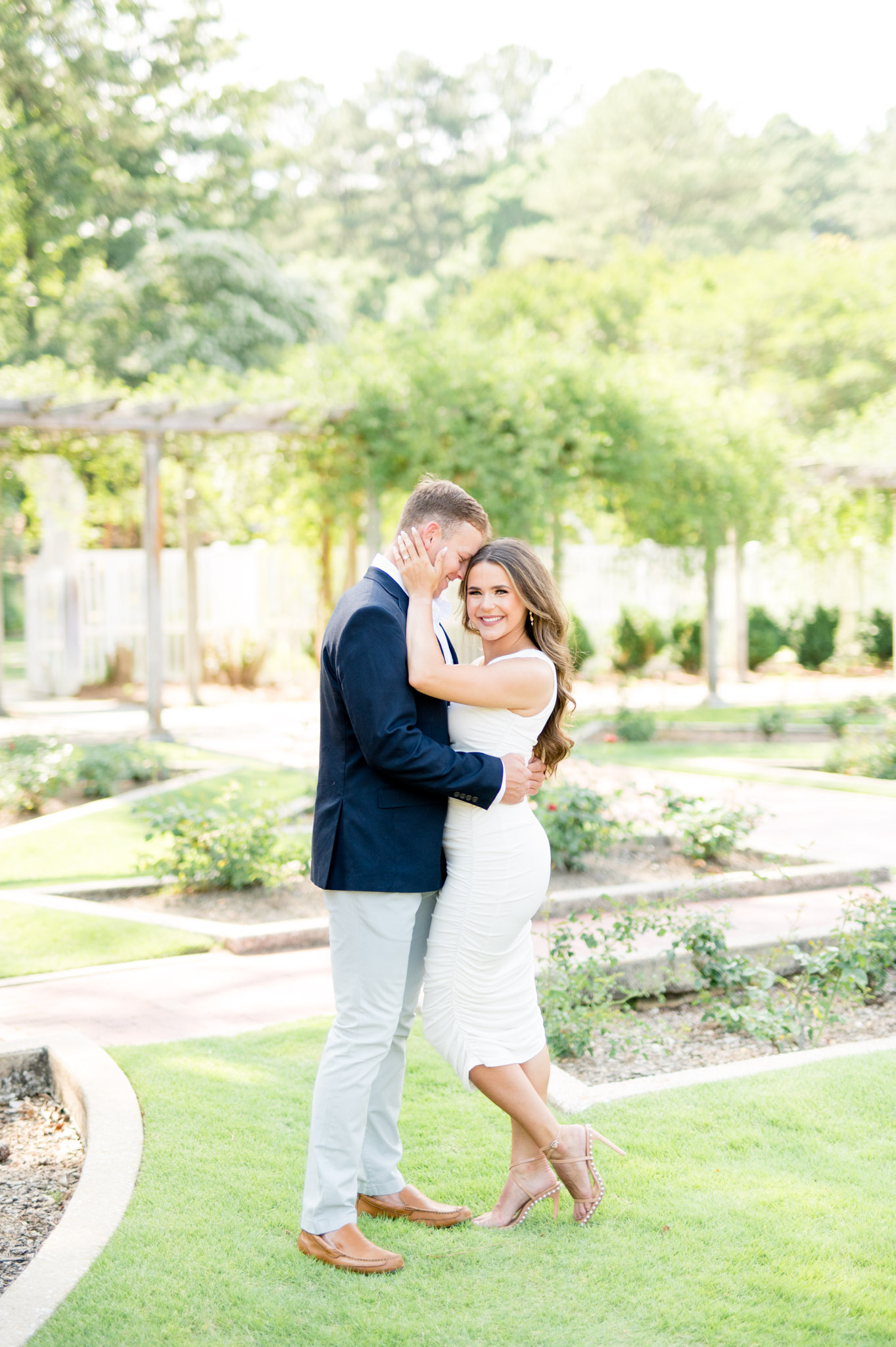 Couple cuddles in rose garden.