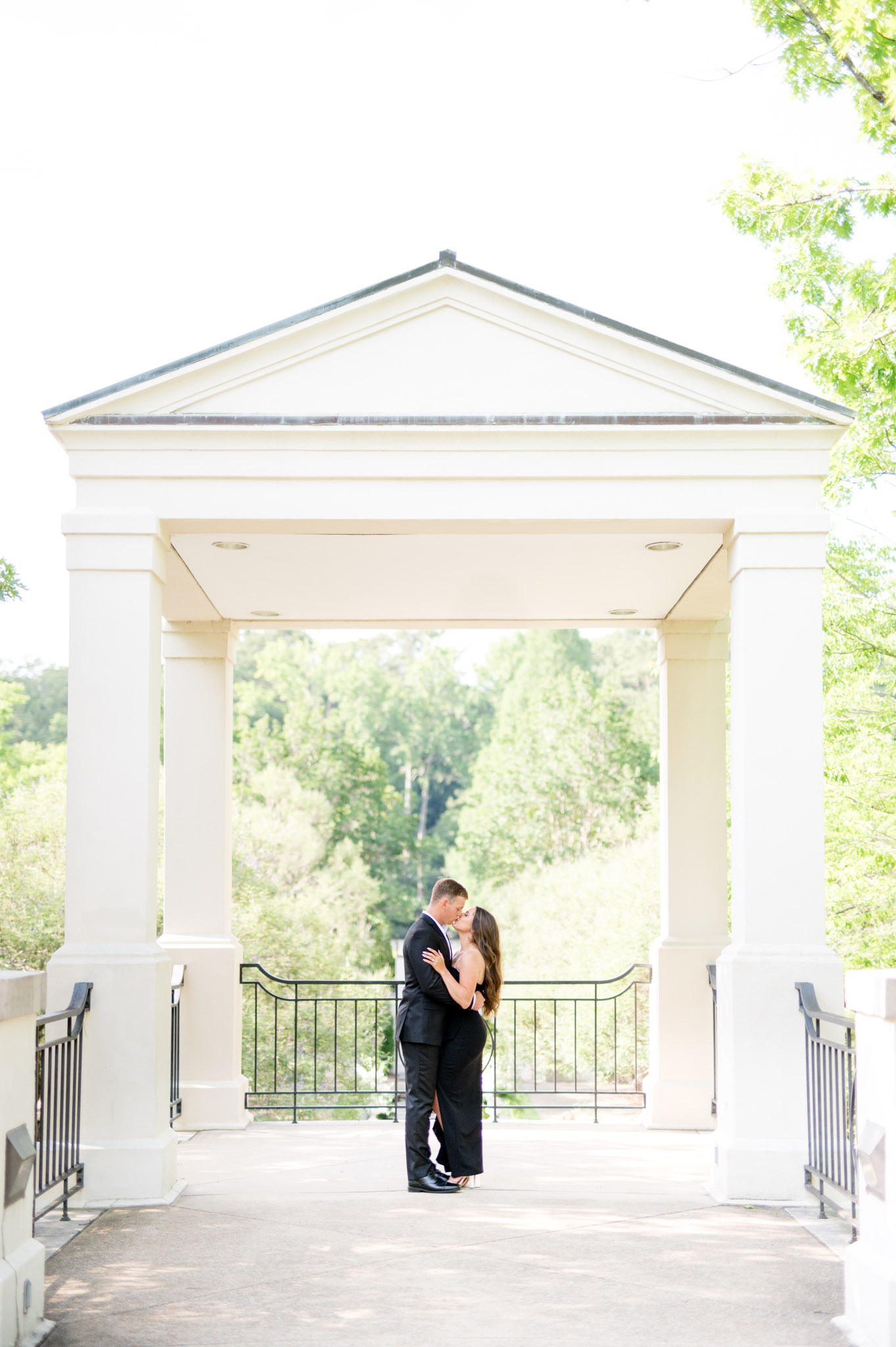 Couple kisses under while pavilion.