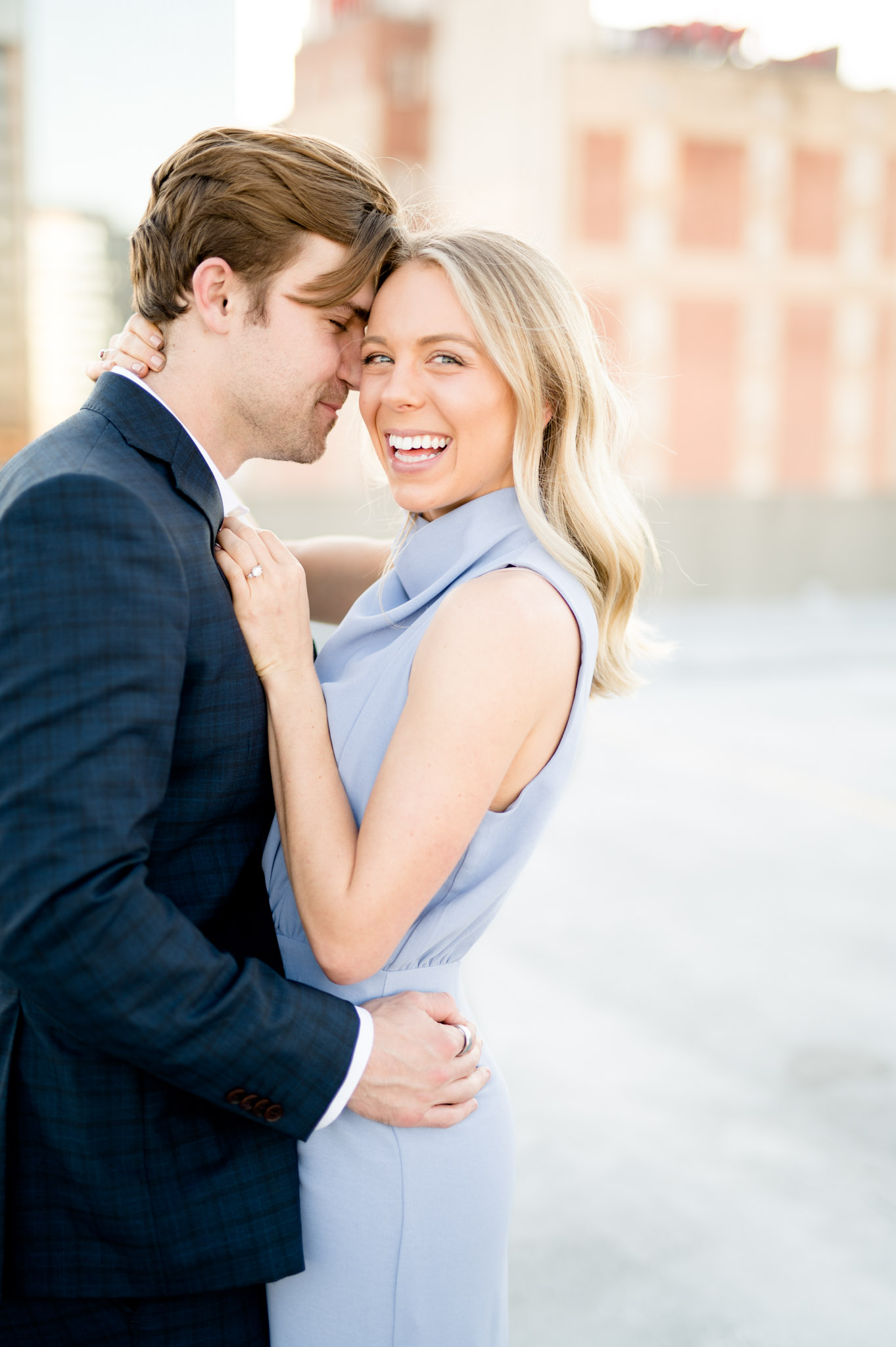 Woman laughs towards camera as man snuggles in.