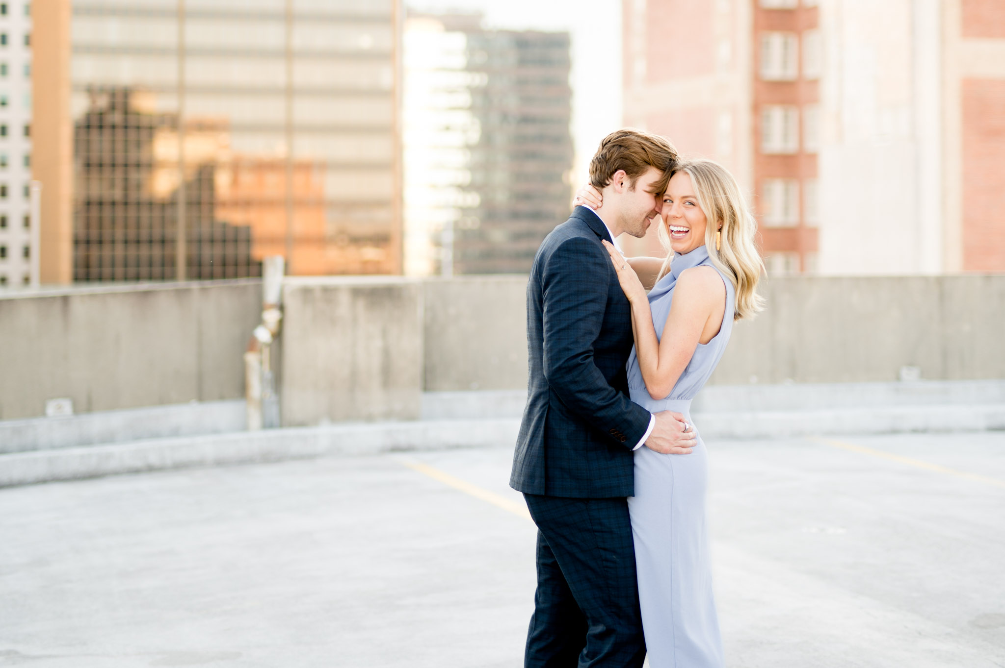 Woman laughs at camera while hugging fiance.