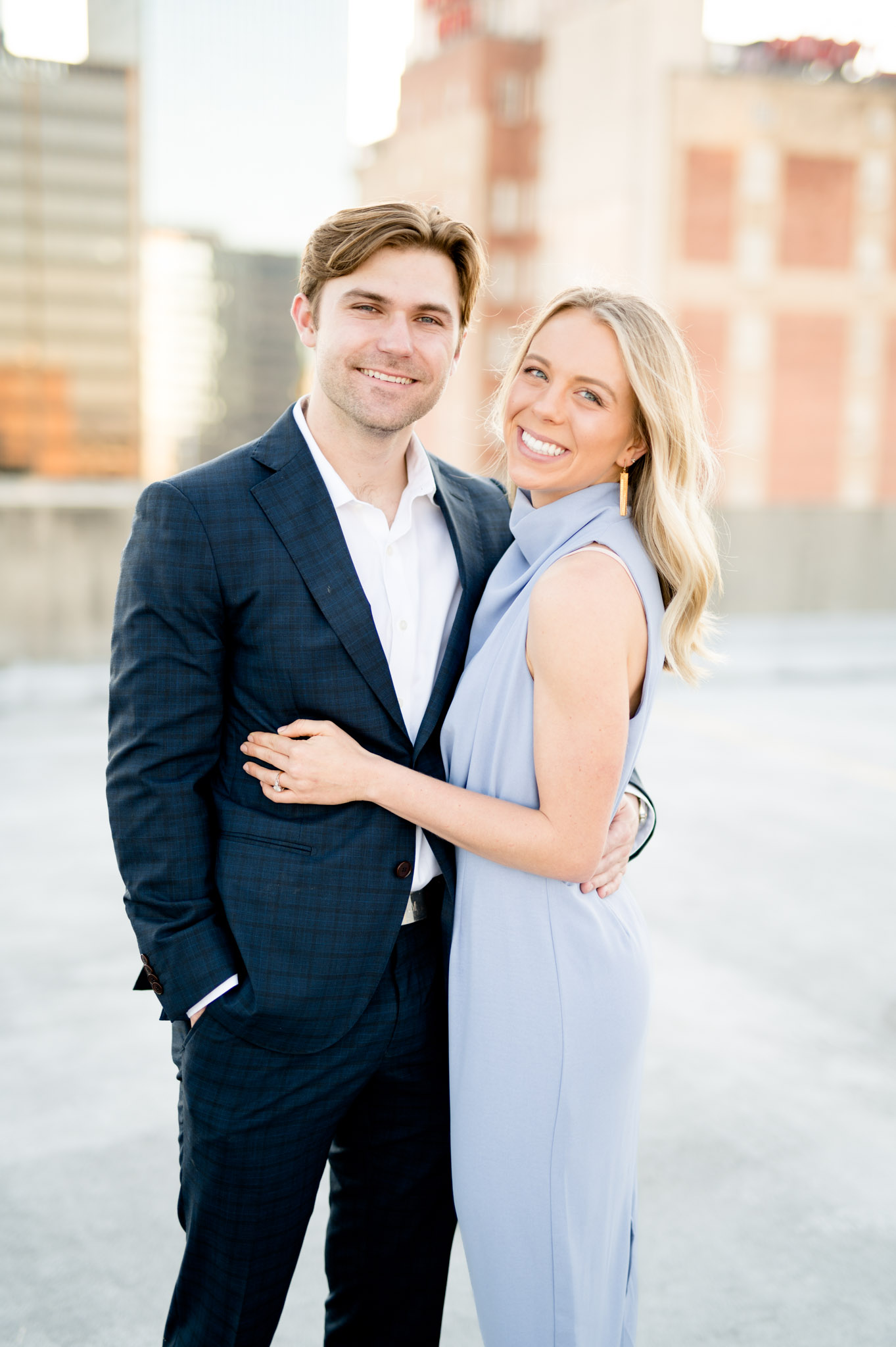 Couple smiles while standing on rooftop.